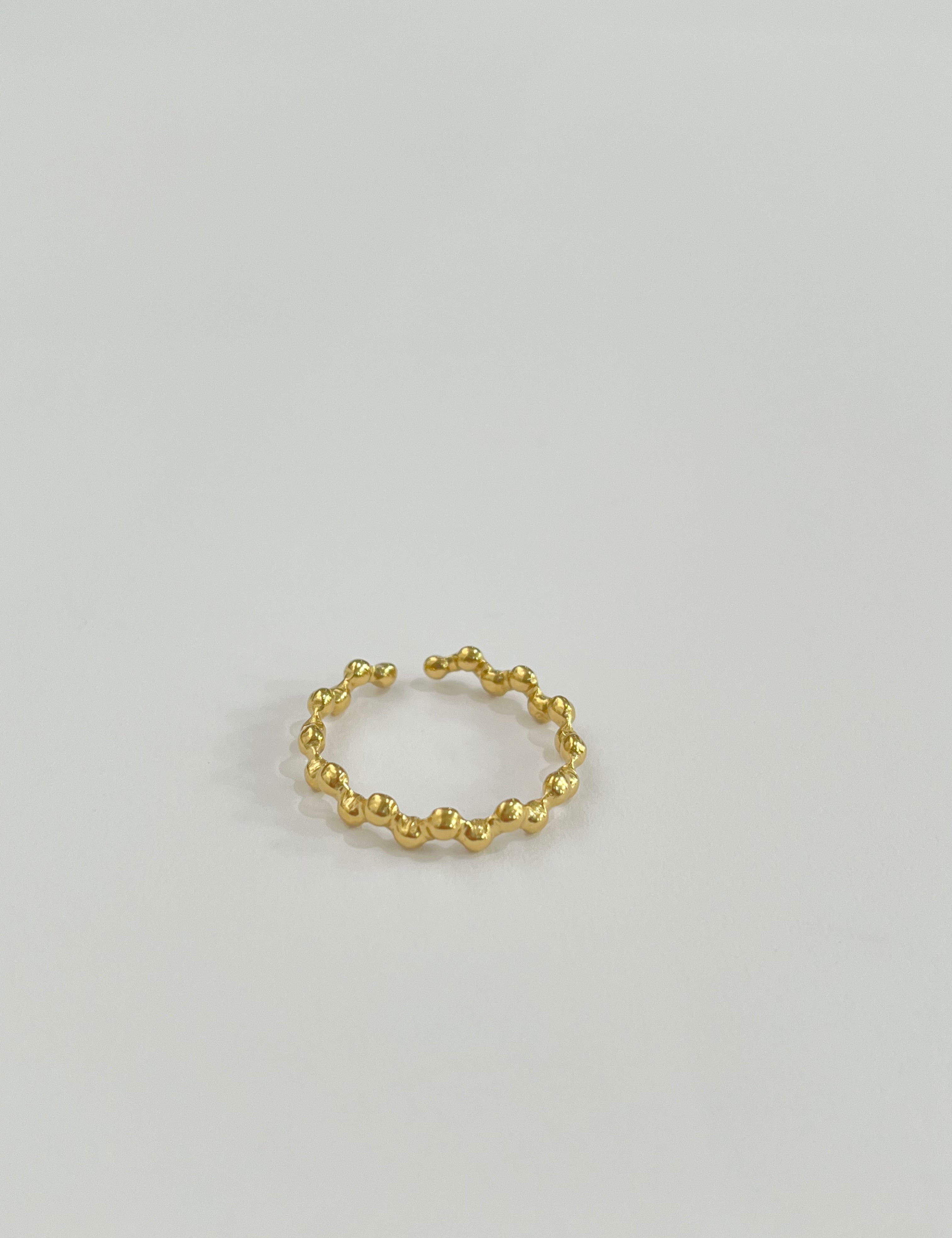 Bague Lory dorée ouverte en petites perles dorées, sur fond gris - Ordiajade