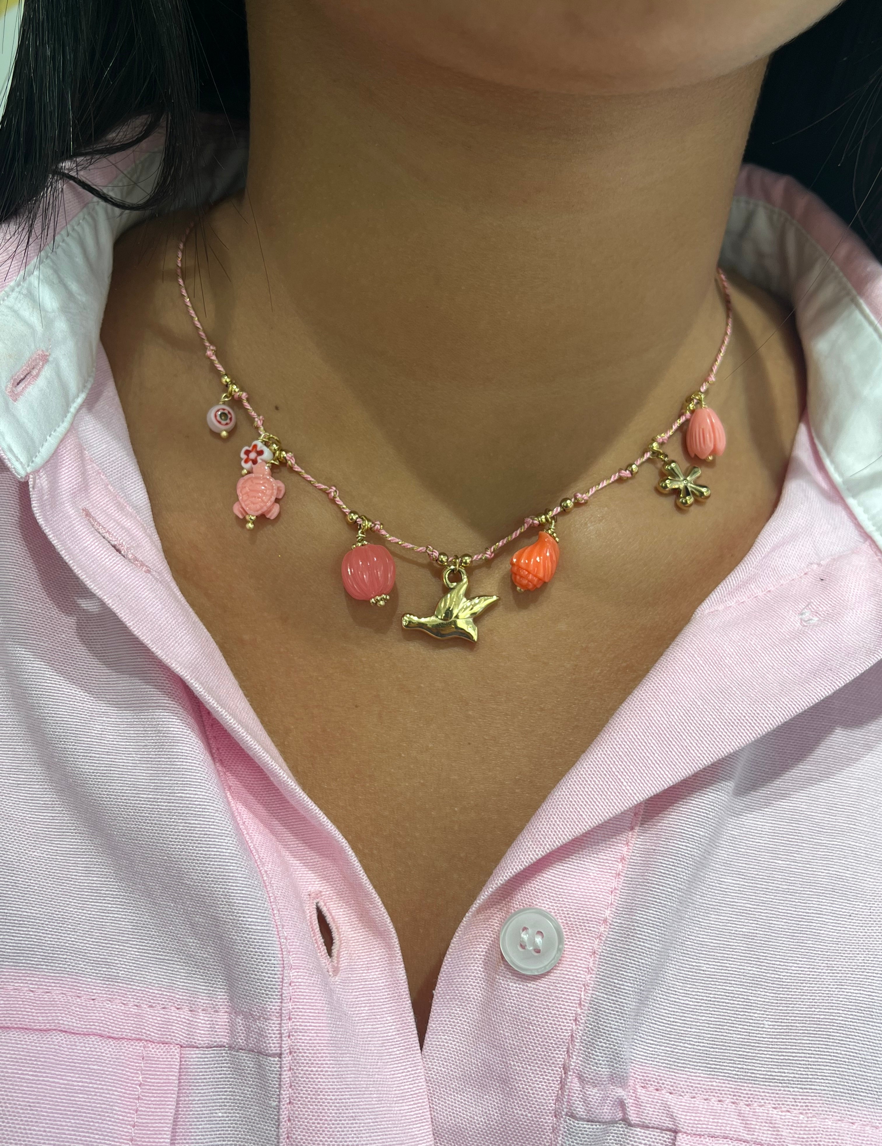 Collier Playa Rose à breloques roses et oiseau doré porté avec une chemise rose - Ordiajade