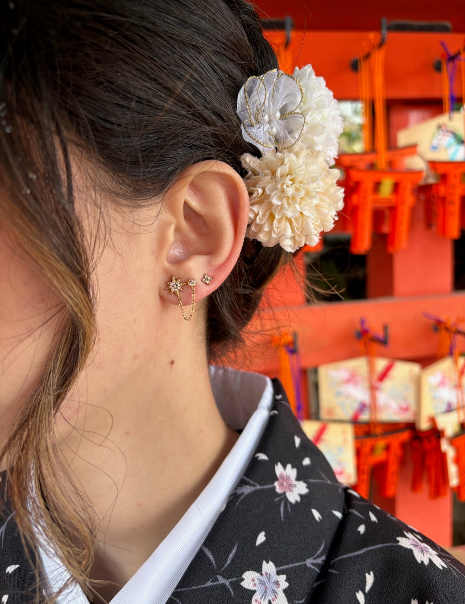 Boucles Hacu double trou dorées : étoile sertie reliée par une chaîne à une petite puce, portées à l'oreille au Japon - Ordiajade