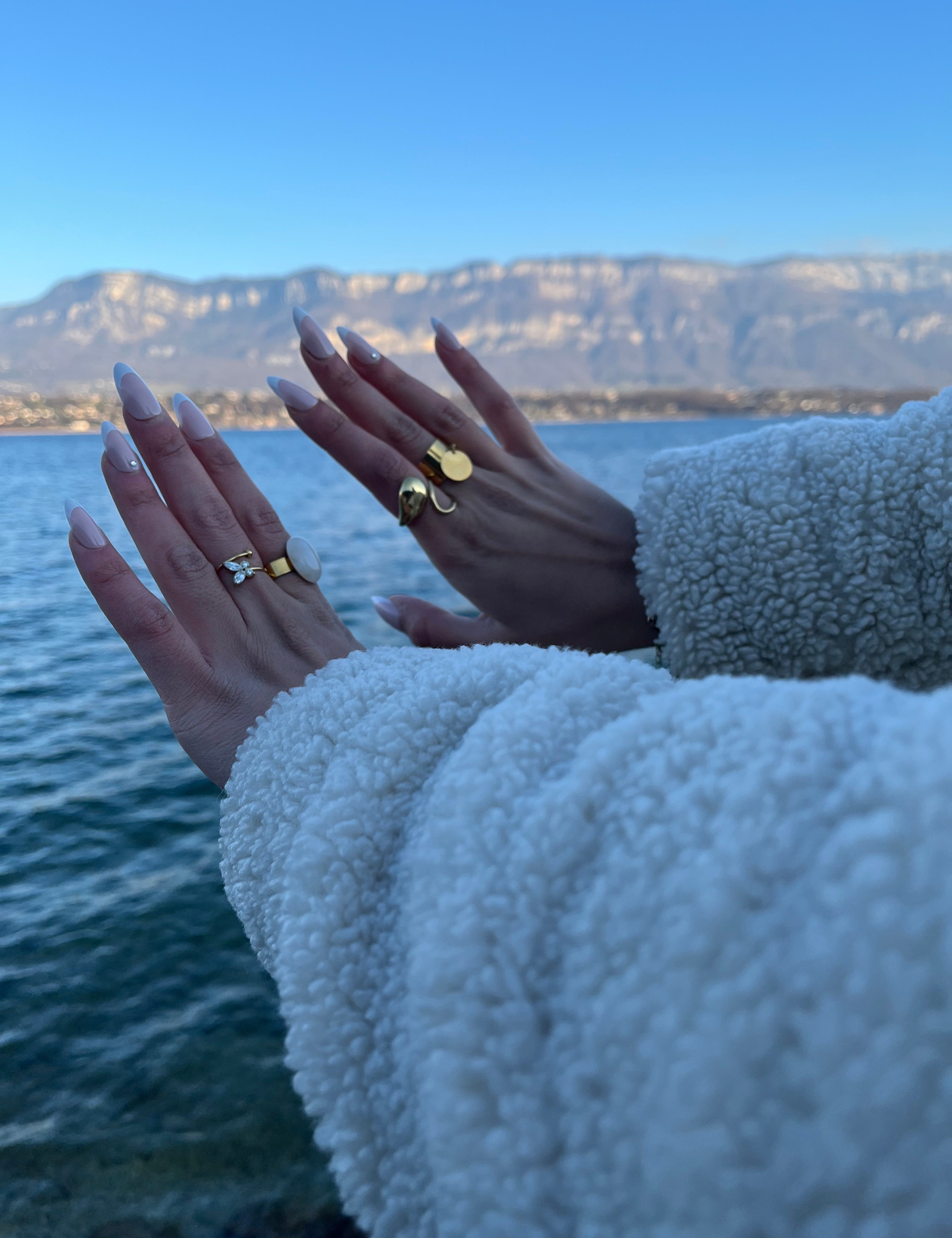 Bague Oraya dorée à pierre naturelle portée au bord d'un lac - Ordiajade