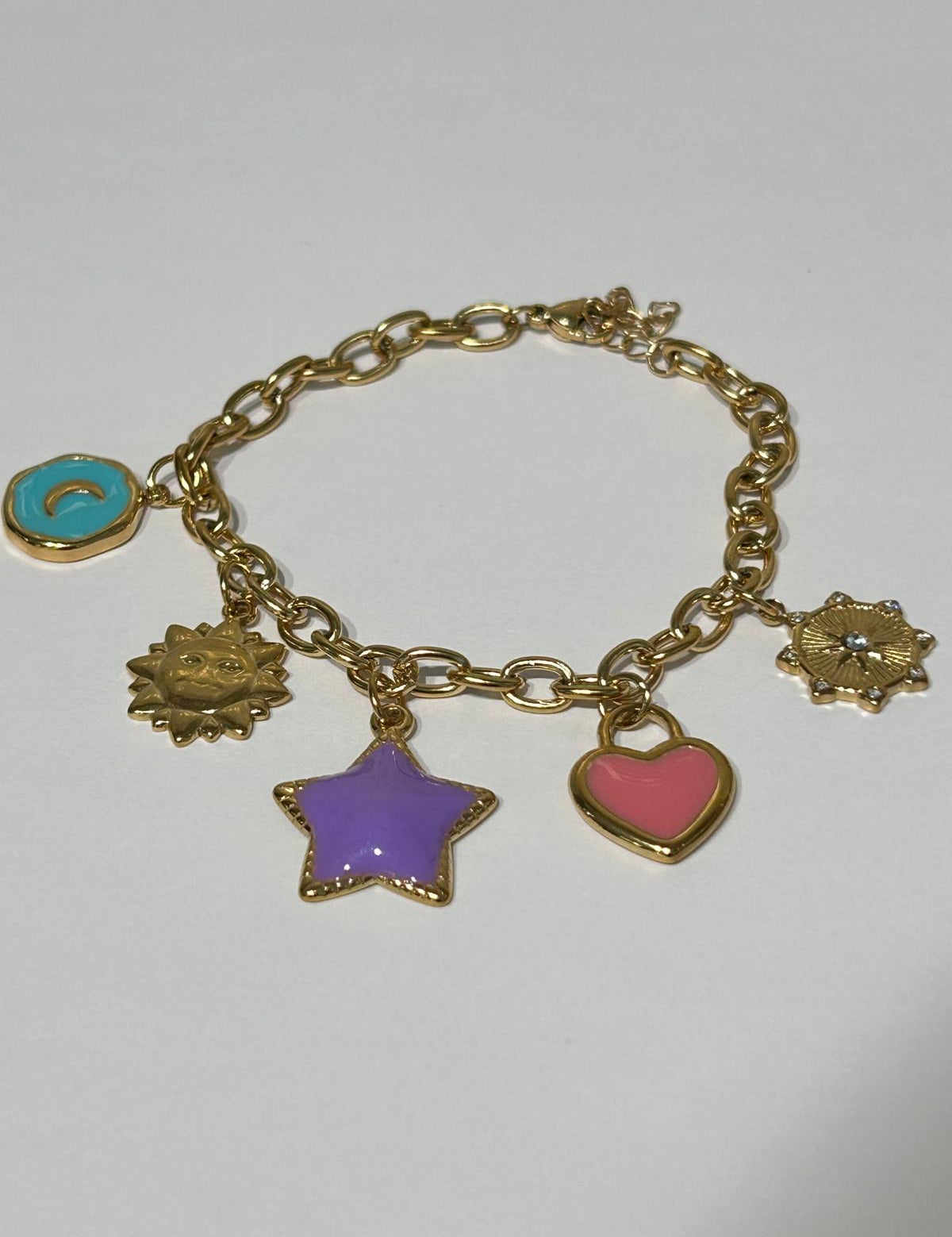 Bracelet Solistar doré à breloques émaillées soleil, étoile et cœur, sur fond gris - Ordiajade