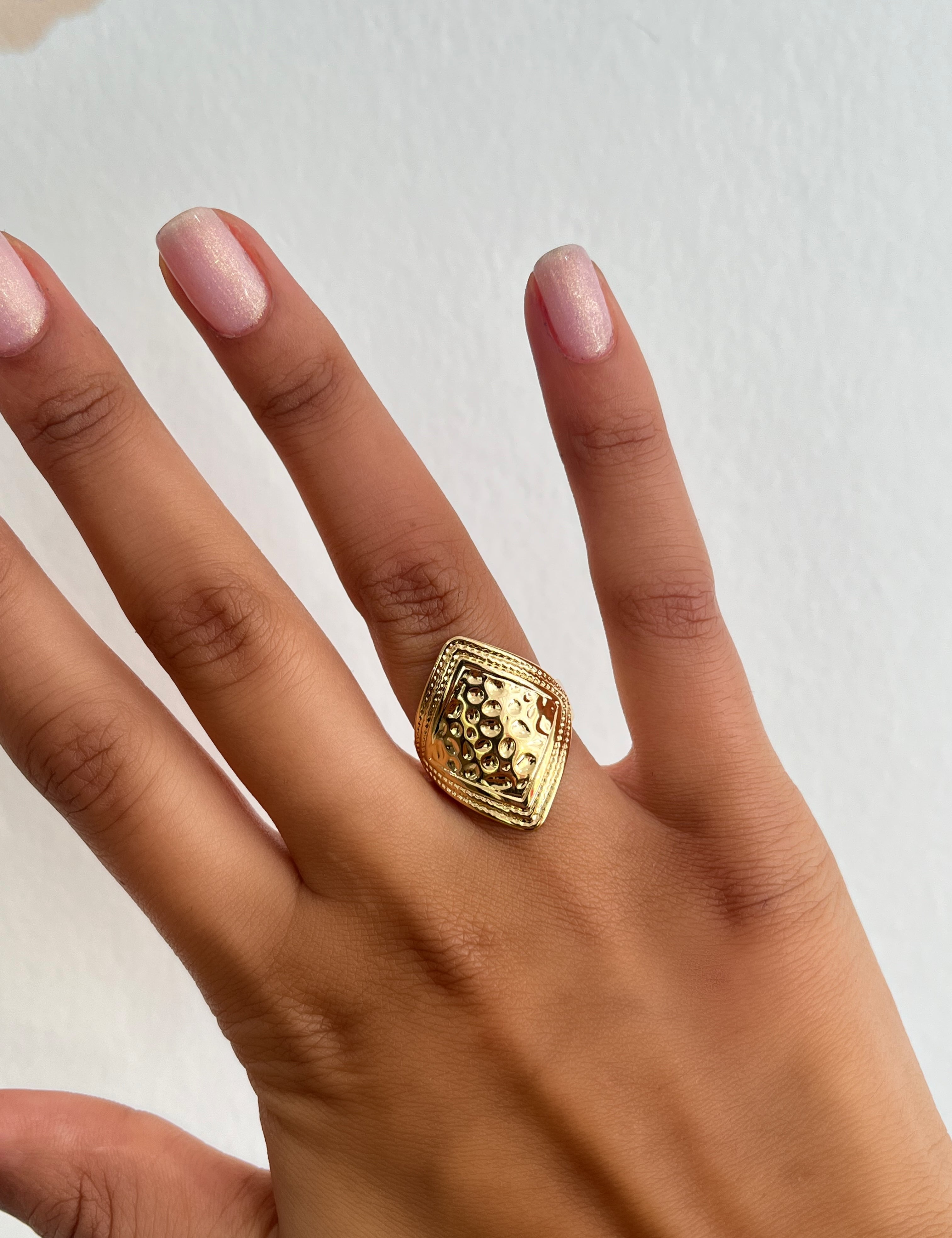 Bague Rituals dorée à plateau ovale texturé, portée au doigt - Ordiajade
