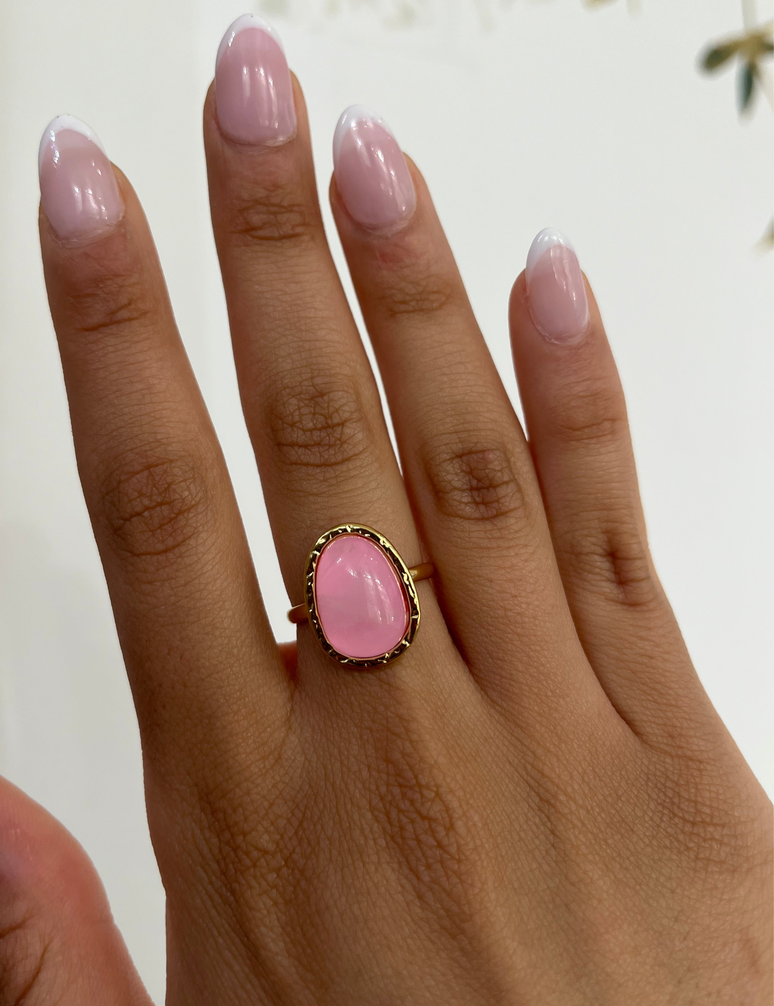 Bague Rosière dorée sertie d'une pierre rose ovale, portée au doigt - Ordiajade