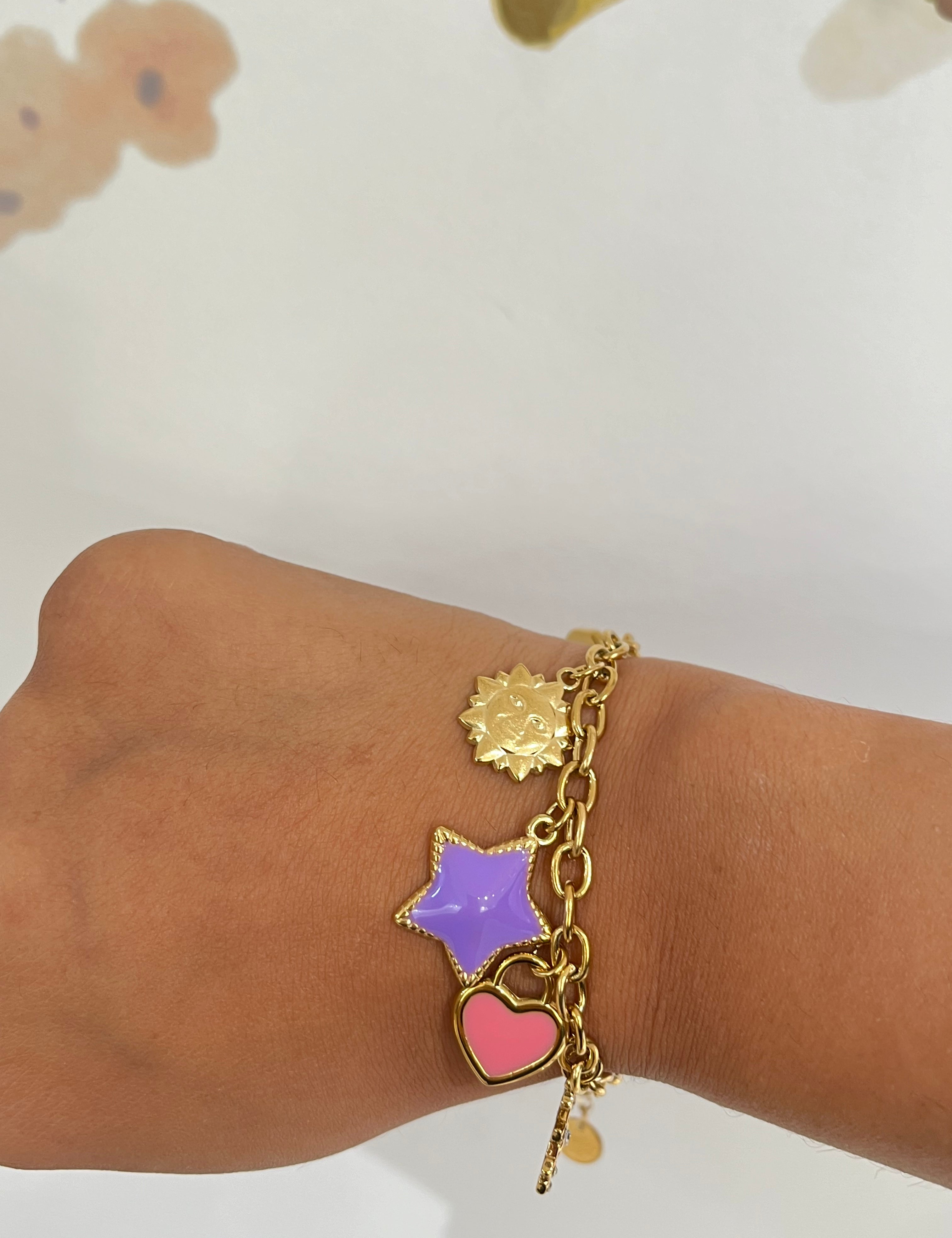 Bracelet Solistar doré à breloques soleil, étoile violette et cœur rose porté au poignet - Ordiajade