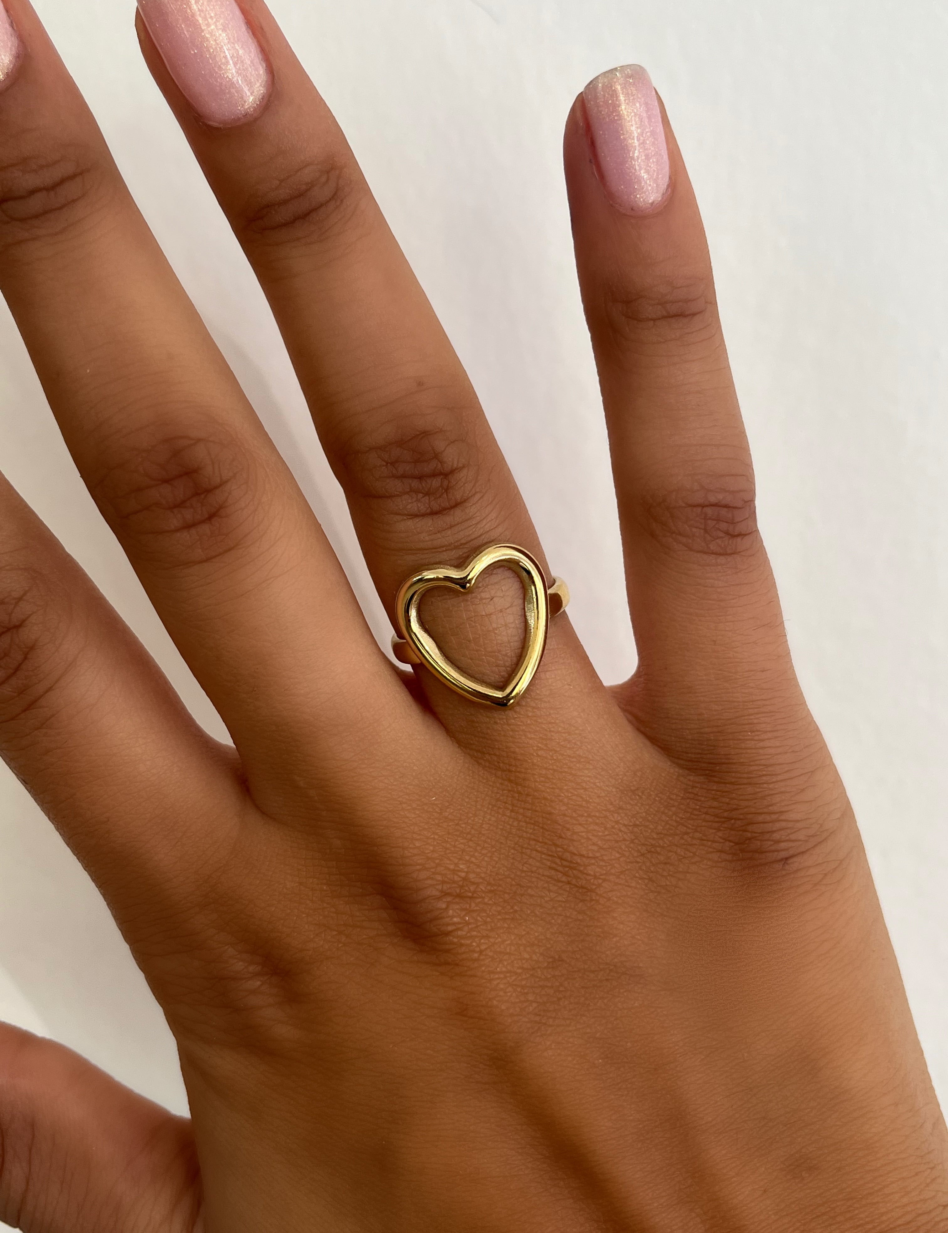 Bague Amore dorée surmontée d'un cœur évidé, portée au doigt - Ordiajade