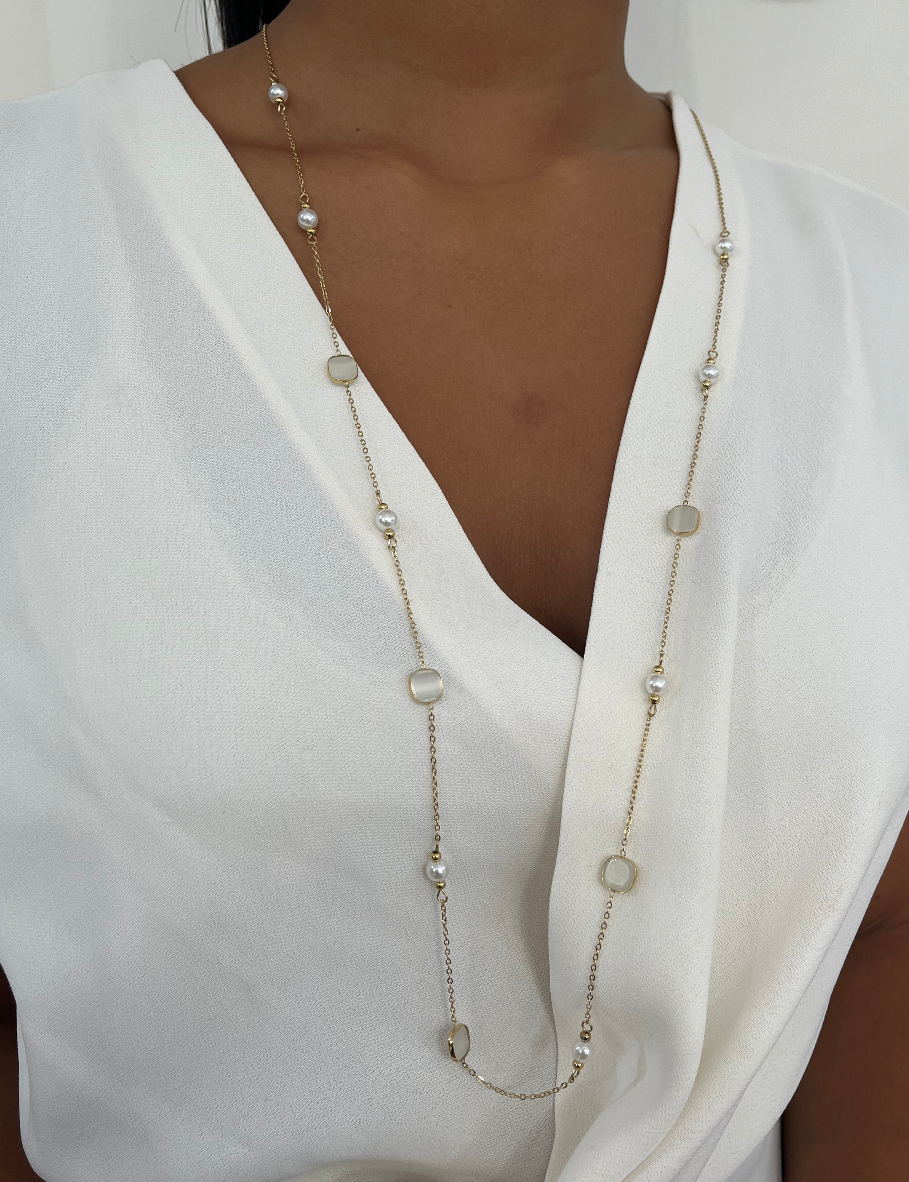 Sautoir long Lolita doré à perles et pierres blanches porté sur un chemisier blanc - Ordiajade