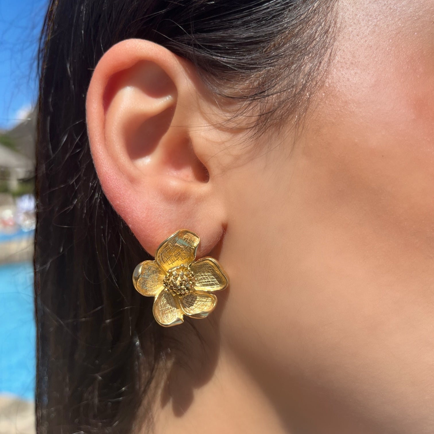 Boucle Nina en forme de fleur portée à l'oreille au bord de la piscine - Ordiajade