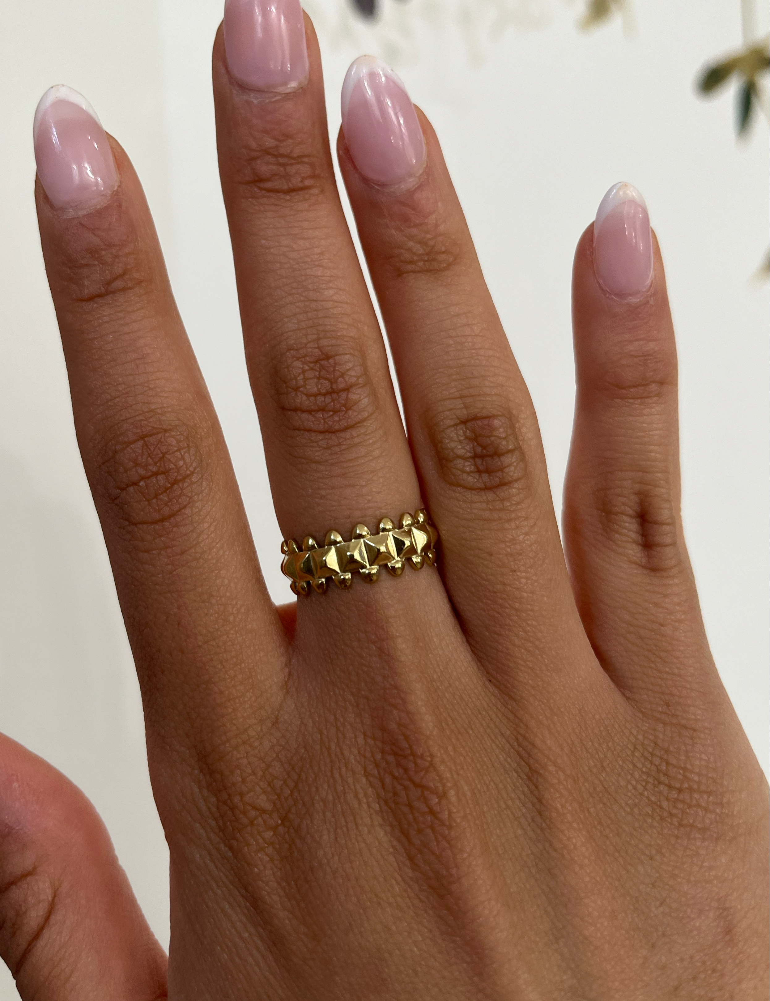 Bague Rolly dorée à motifs en pointe bordés de billes, portée au doigt - Ordiajade