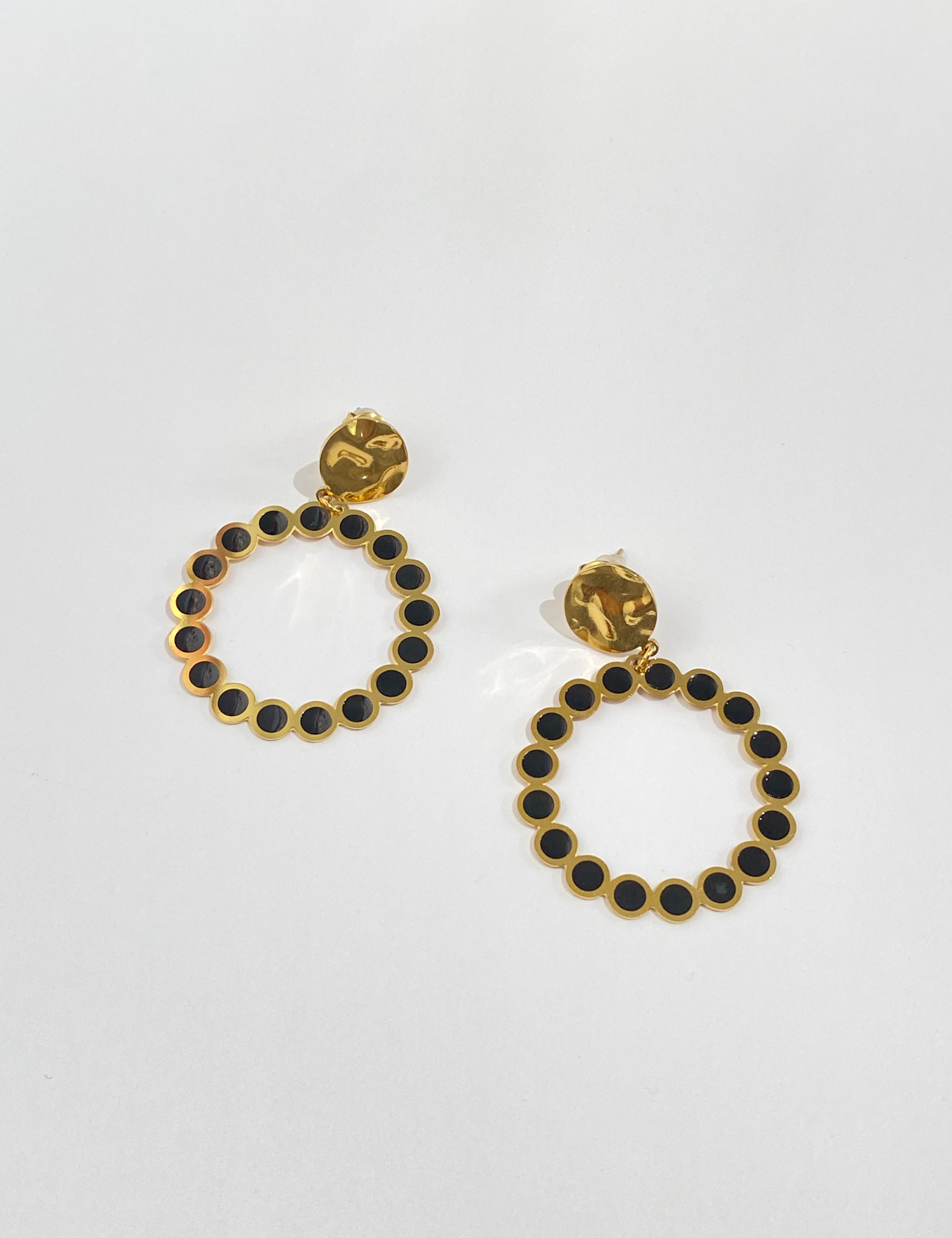 Paire de boucles Calm dorées à anneau serti de pierres noires, sur fond gris - Ordiajade