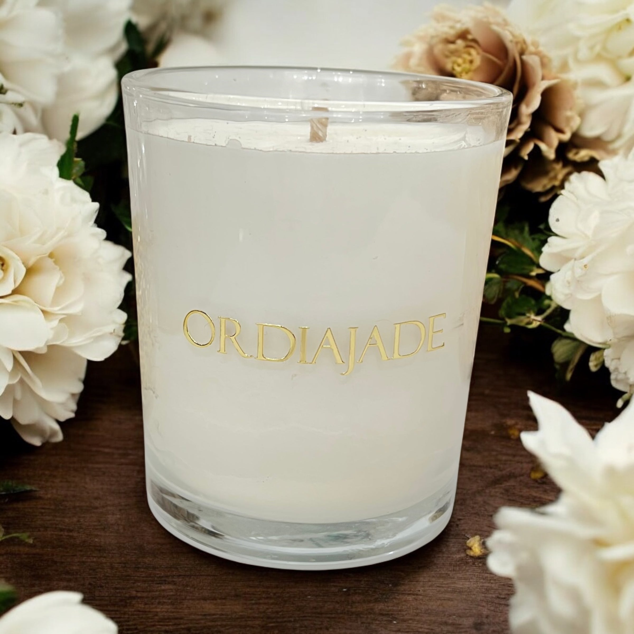 Bougie bijou Ordiajade en cire de soja entourée de fleurs blanches