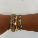 Poignet looké avec une accumulation de plusieurs bracelets dorés dont le bracelet Swinie - Ordiajade