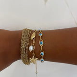 Poignet looké avec une accumulation de plusieurs bracelets dorés dont le bracelet Swinie - Ordiajade