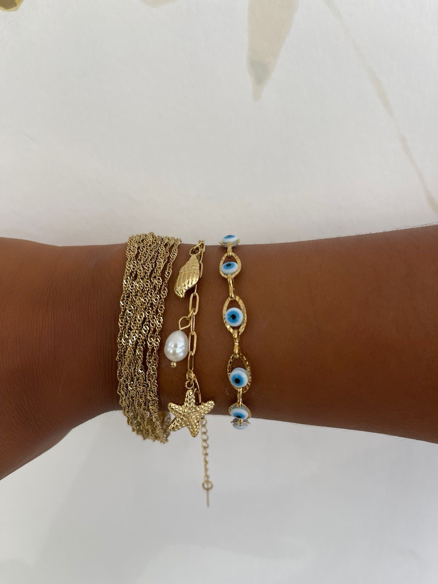 Poignet looké avec une accumulation de plusieurs bracelets dorés dont le bracelet Swinie - Ordiajade