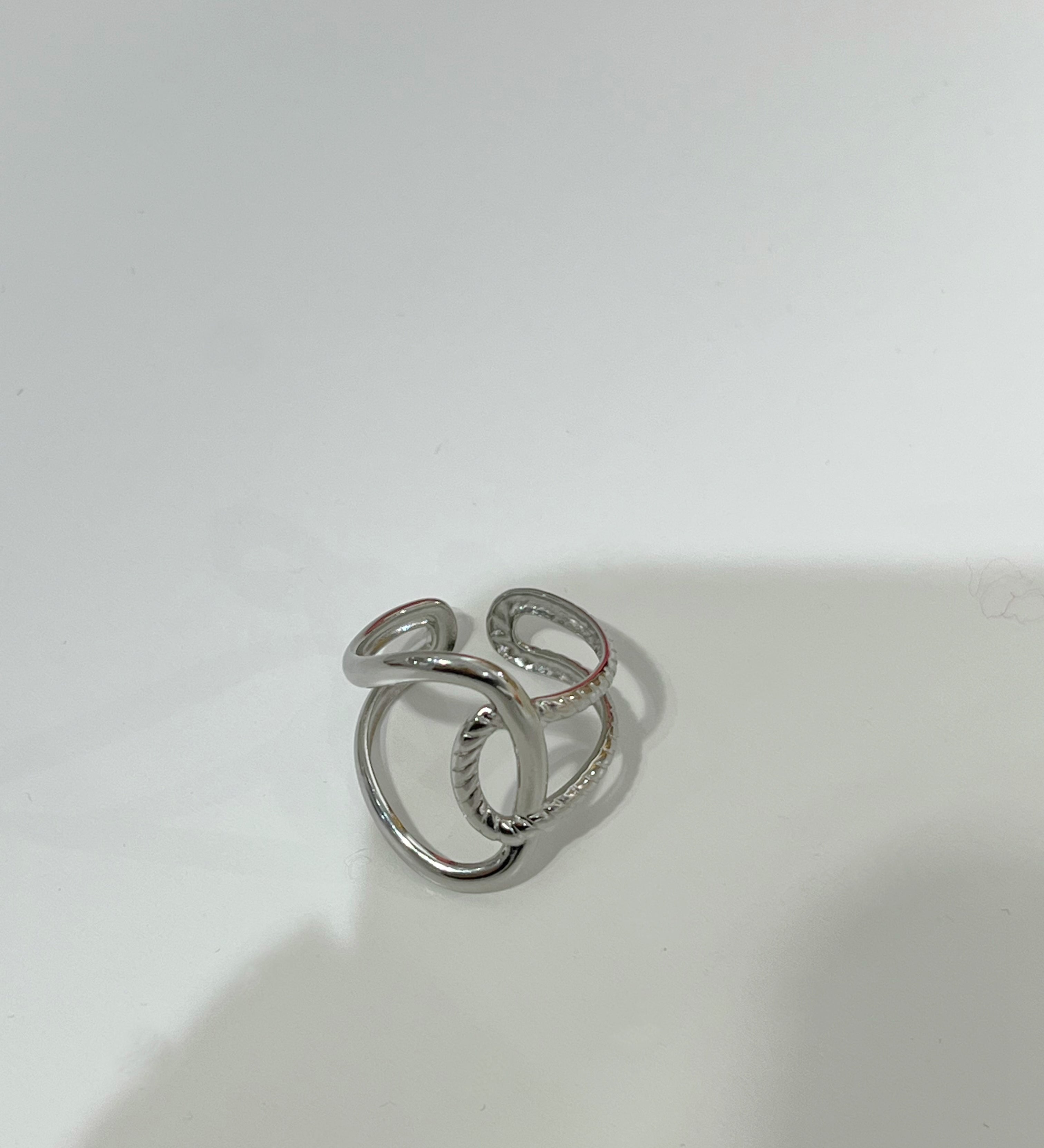 Bague ajustable Gavy argentée en acier inoxydable aux anneaux entrelacés posée à plat - Ordiajade