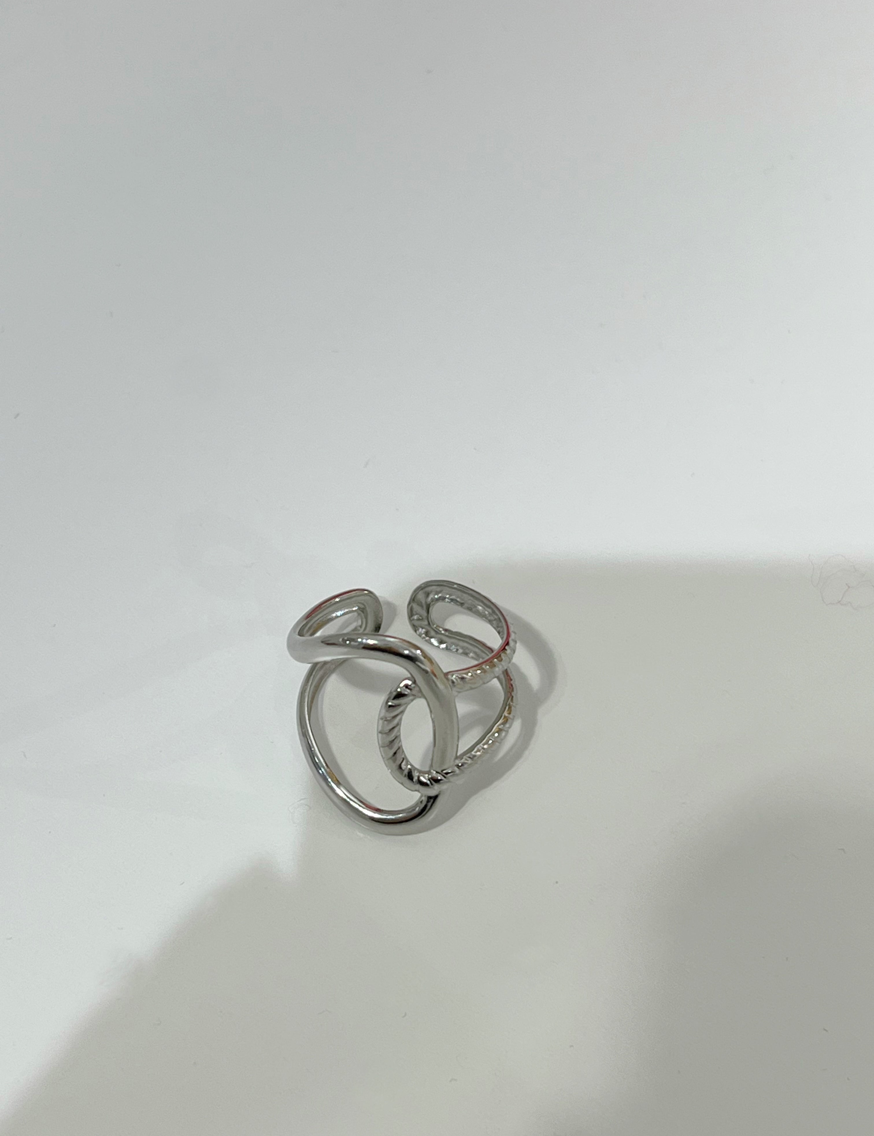 Bague ajustable Gavy argentée en acier inoxydable aux anneaux entrelacés posée à plat - Ordiajade