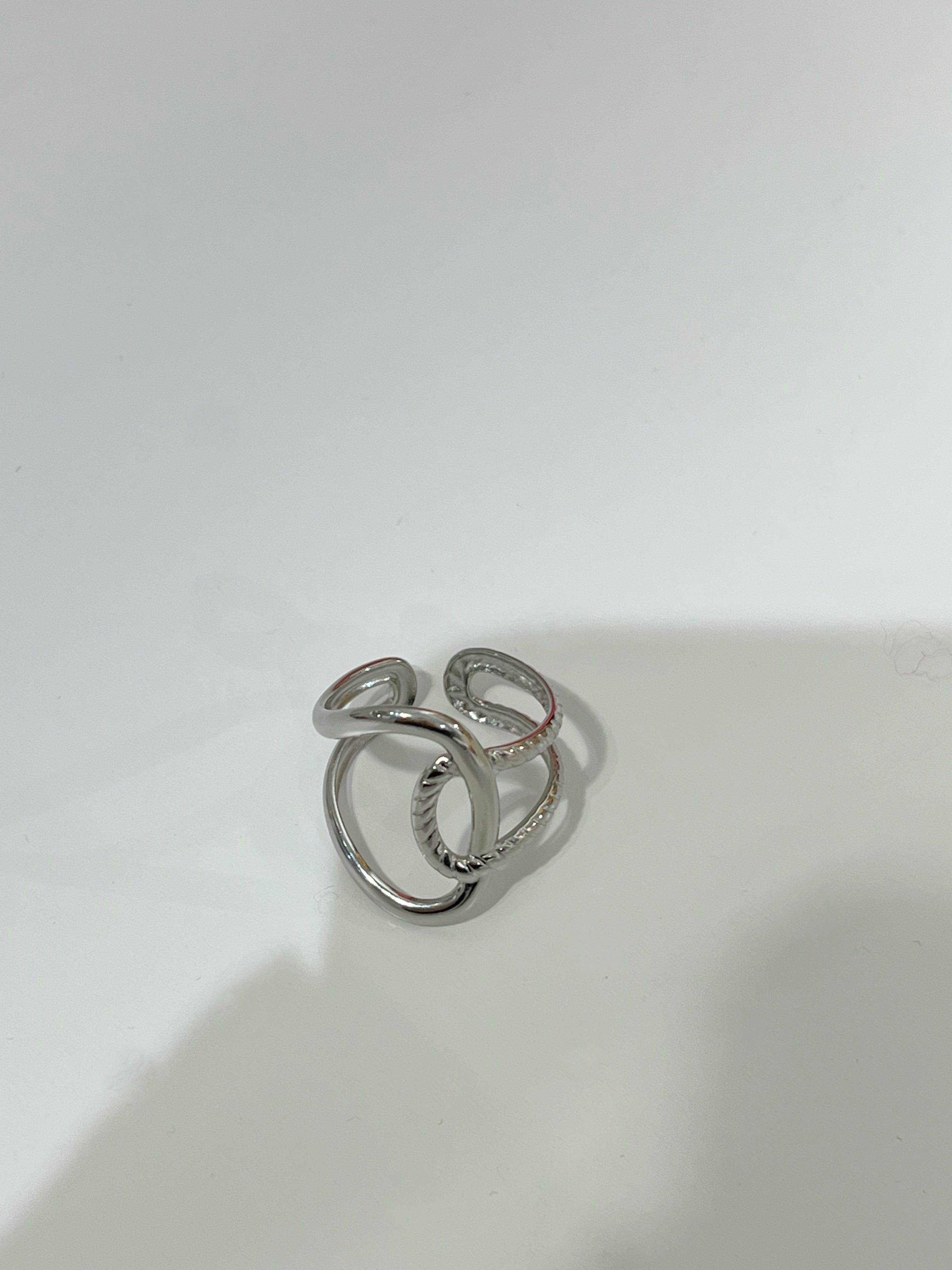 Bague ajustable Gavy argentée en acier inoxydable aux anneaux entrelacés posée à plat - Ordiajade