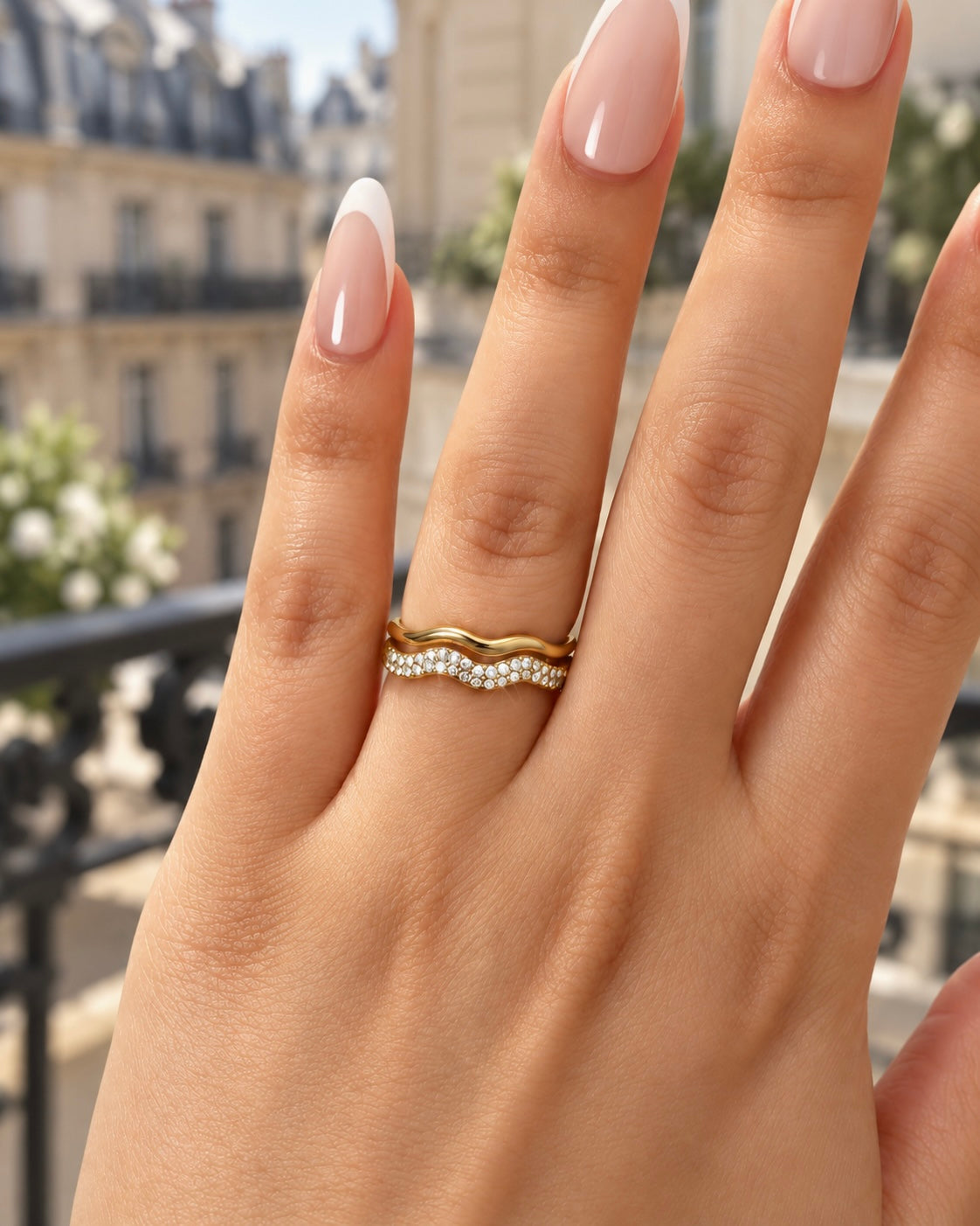Bague Jadore ondulée dorée et pavée portée à l'annulaire, balcon parisien en arrière-plan - Ordiajade