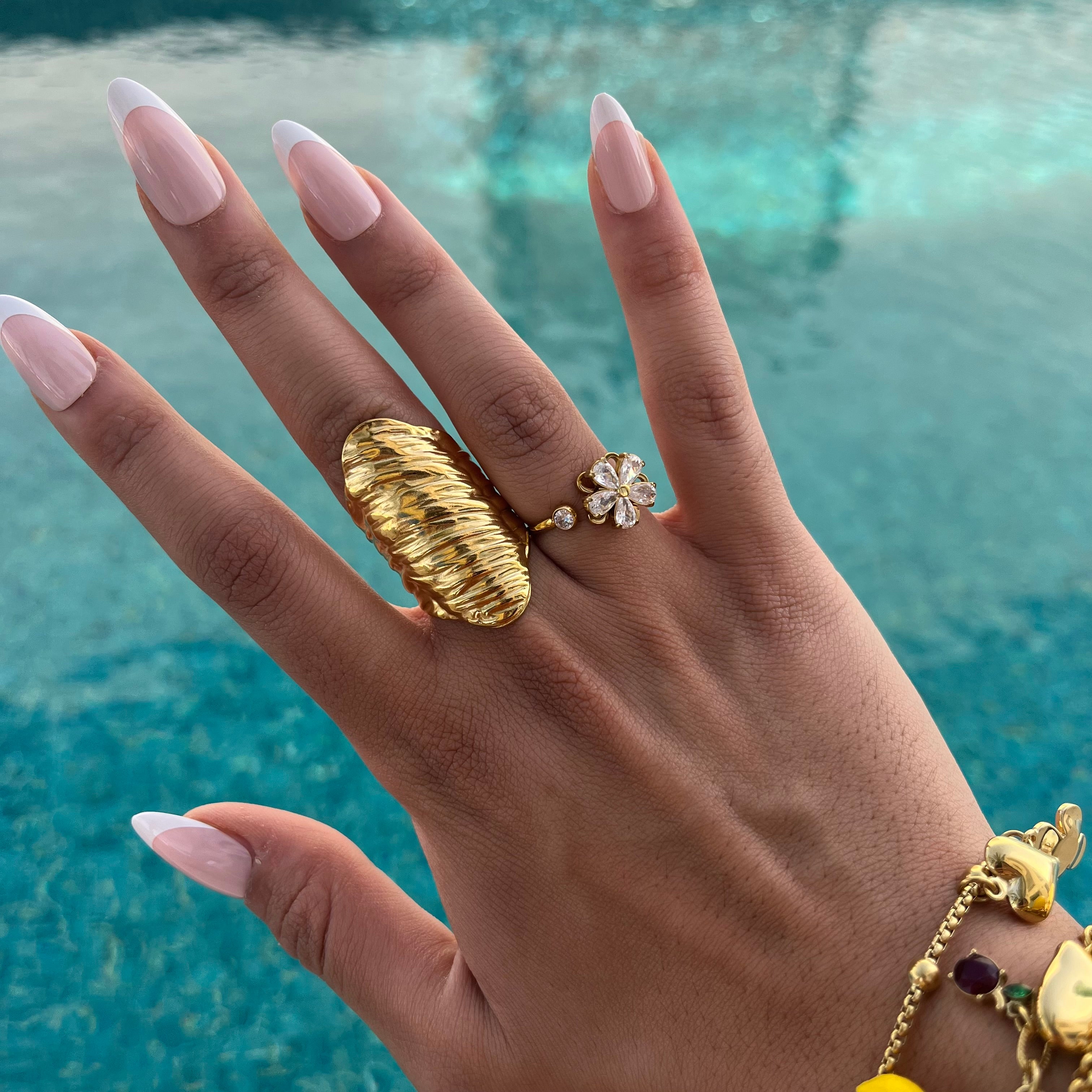Bague Mao en acier inoxydable doré large et striée portée au doigt au bord de la piscine - Ordiajade