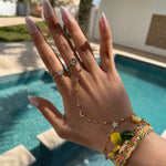 Bijou de main astronomique doré et perles fines porté en accumulation avec des bracelets.