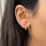 Gros plan d'une mini créole Gold White en acier inoxydable pavée de strass portée à l'oreille - Ordiajade