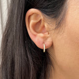 Gros plan d'une mini créole Gold White en acier inoxydable pavée de strass portée à l'oreille - Ordiajade