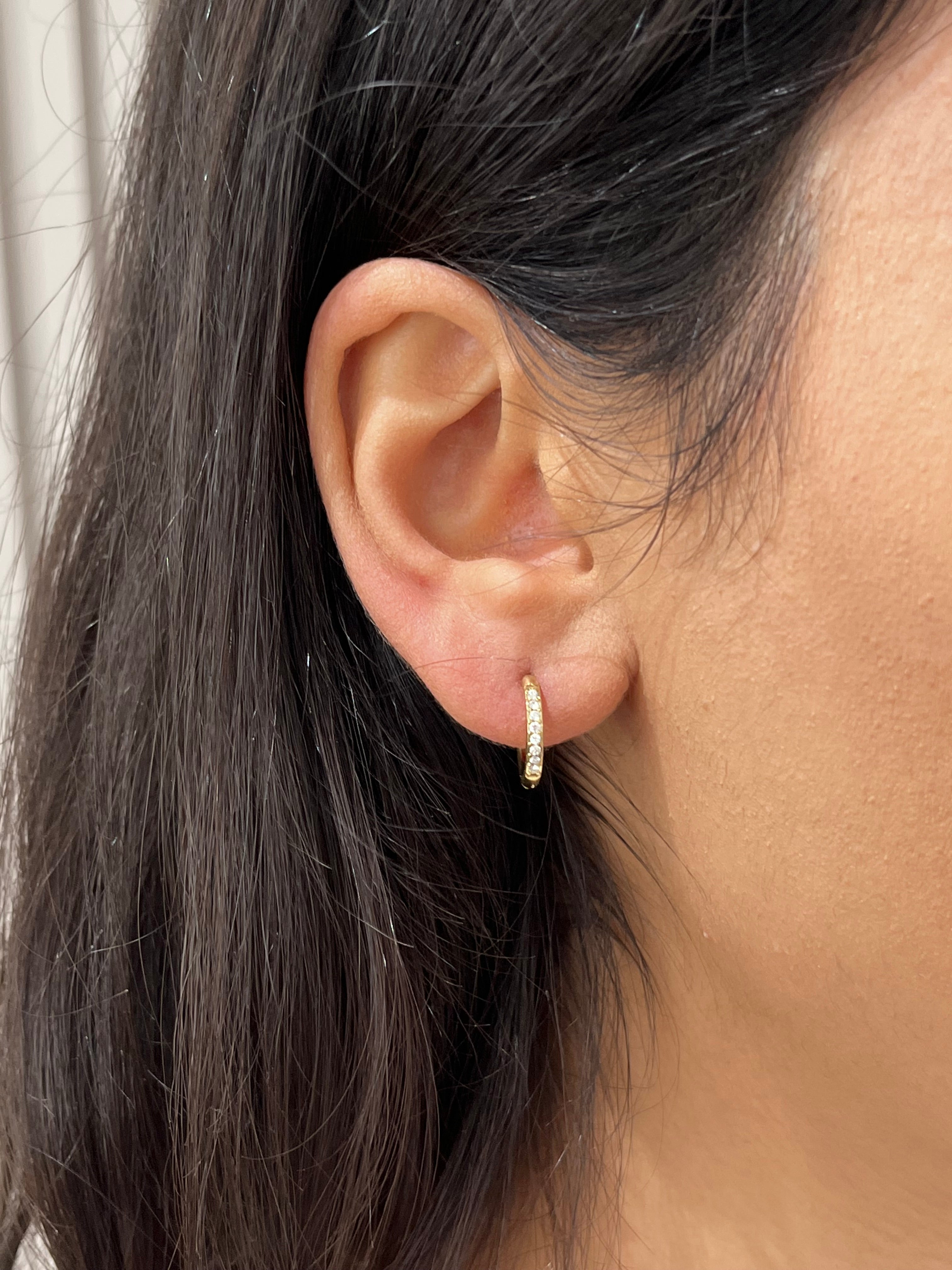 Gros plan d'une mini créole Gold White en acier inoxydable pavée de strass portée à l'oreille - Ordiajade
