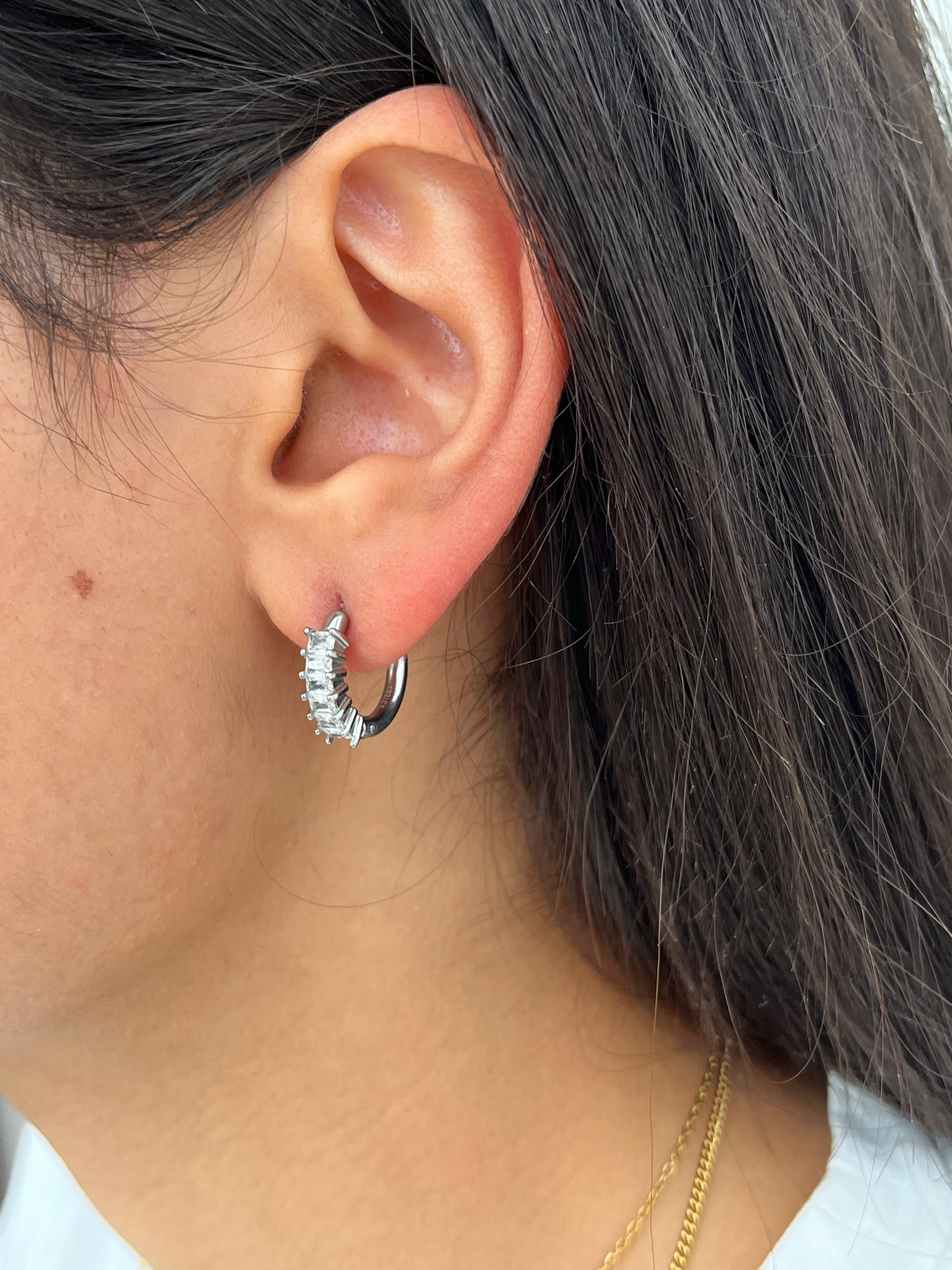 Gros plan des boucles d'oreilles créoles Juliette argentées en acier inoxydable avec cristaux portées à l'oreille - Ordiajade