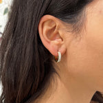 Gros plan de la boucle d'oreille créole huggie Same dorée pavée de strass portée au lobe - Ordiajade