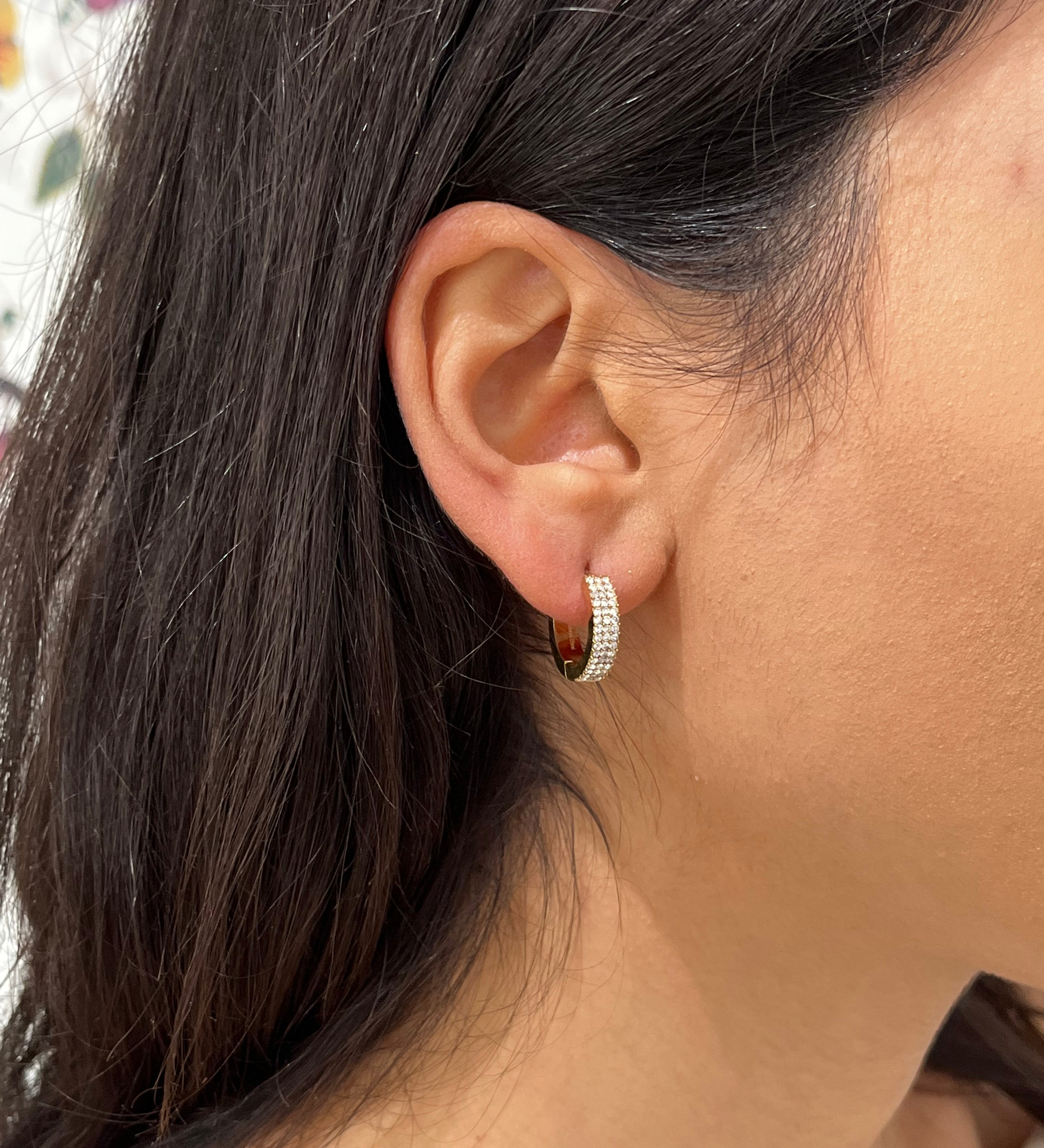 Gros plan de la boucle d'oreille créole huggie Same dorée pavée de strass portée au lobe - Ordiajade