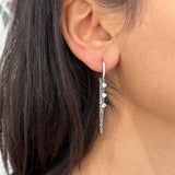 Gros plan des boucles d'oreilles pendantes en acier inoxydable argentées Yamina portées - Ordiajade