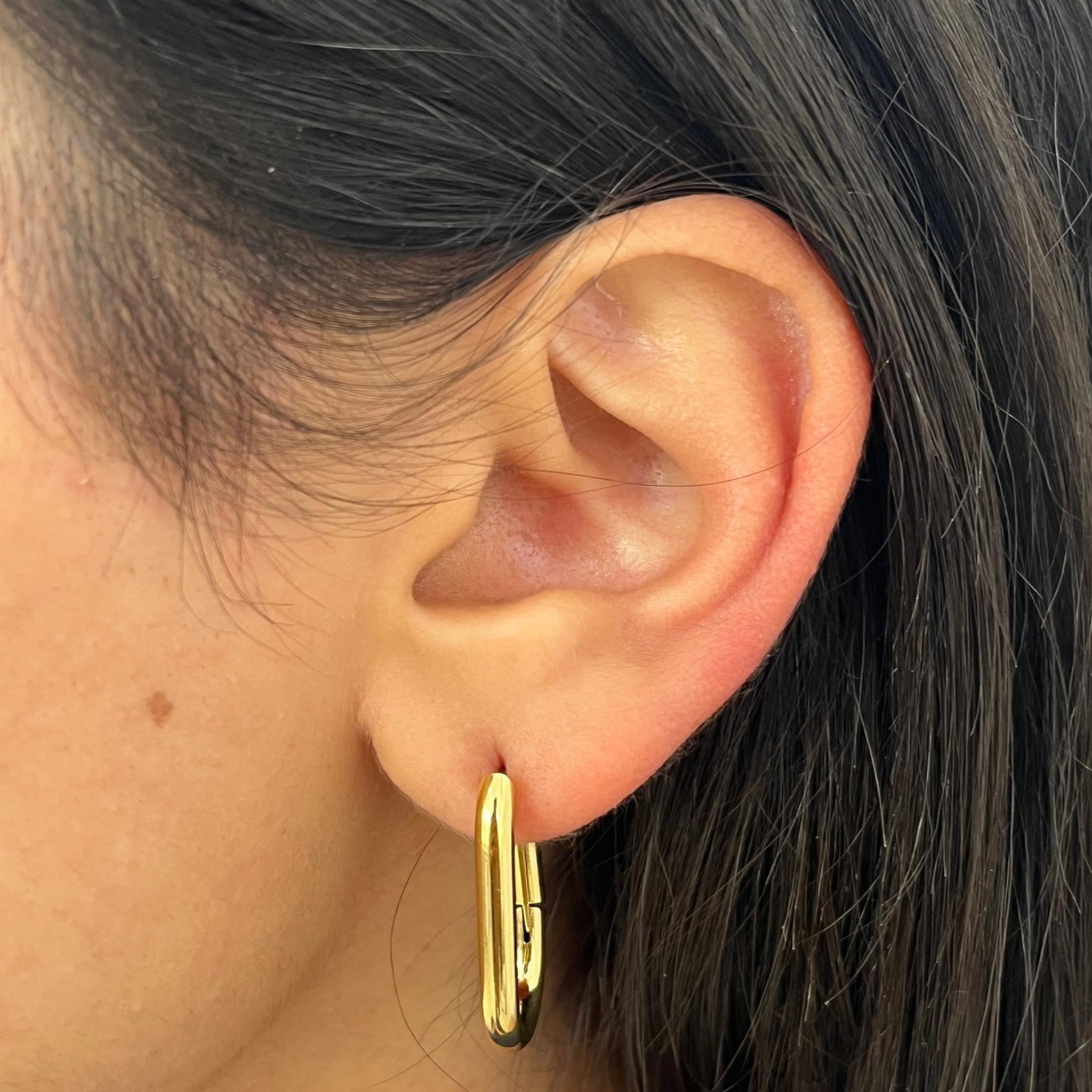 "Gros plan sur les boucles d'oreilles Karen dorées portées, style minimaliste et chic