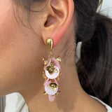 Grandes boucles d'oreilles Rich dorées avec motifs fleurs rose et dorées portées de profil.