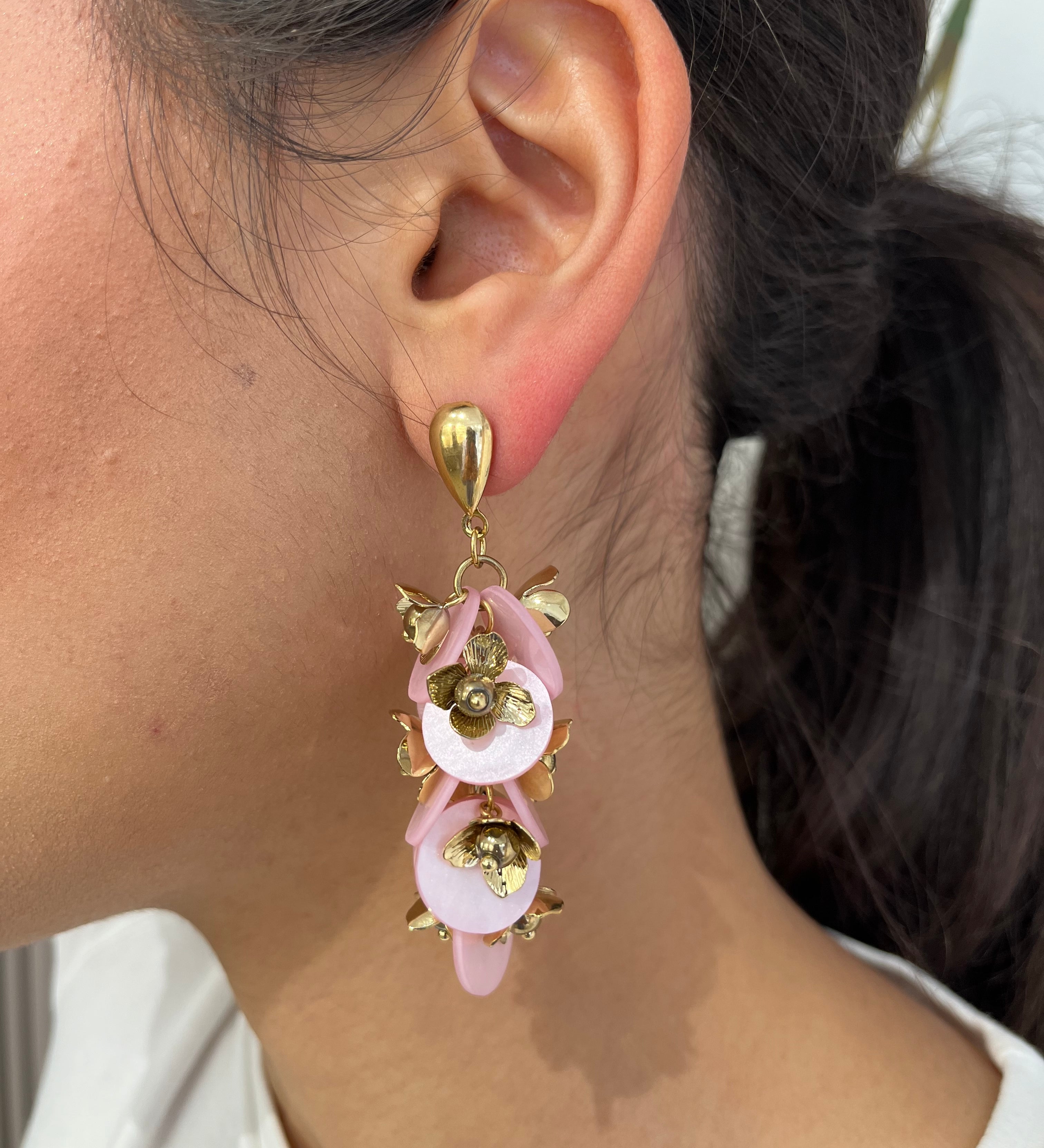 Grandes boucles d'oreilles Rich dorées avec motifs fleurs rose et dorées portées de profil.