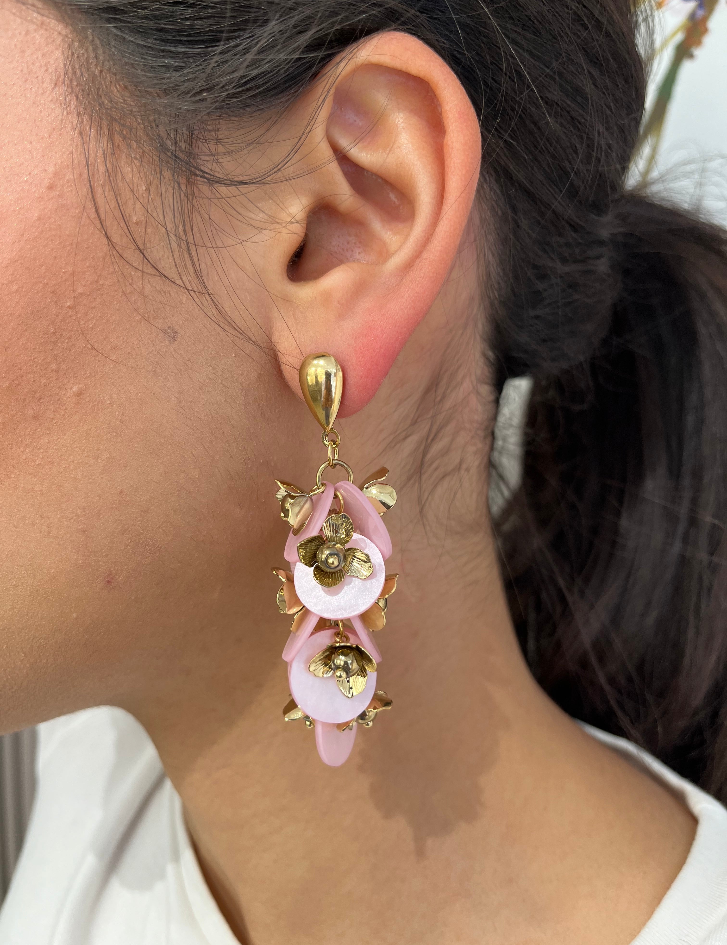 Grandes boucles d'oreilles Rich dorées avec motifs fleurs rose et dorées portées de profil.