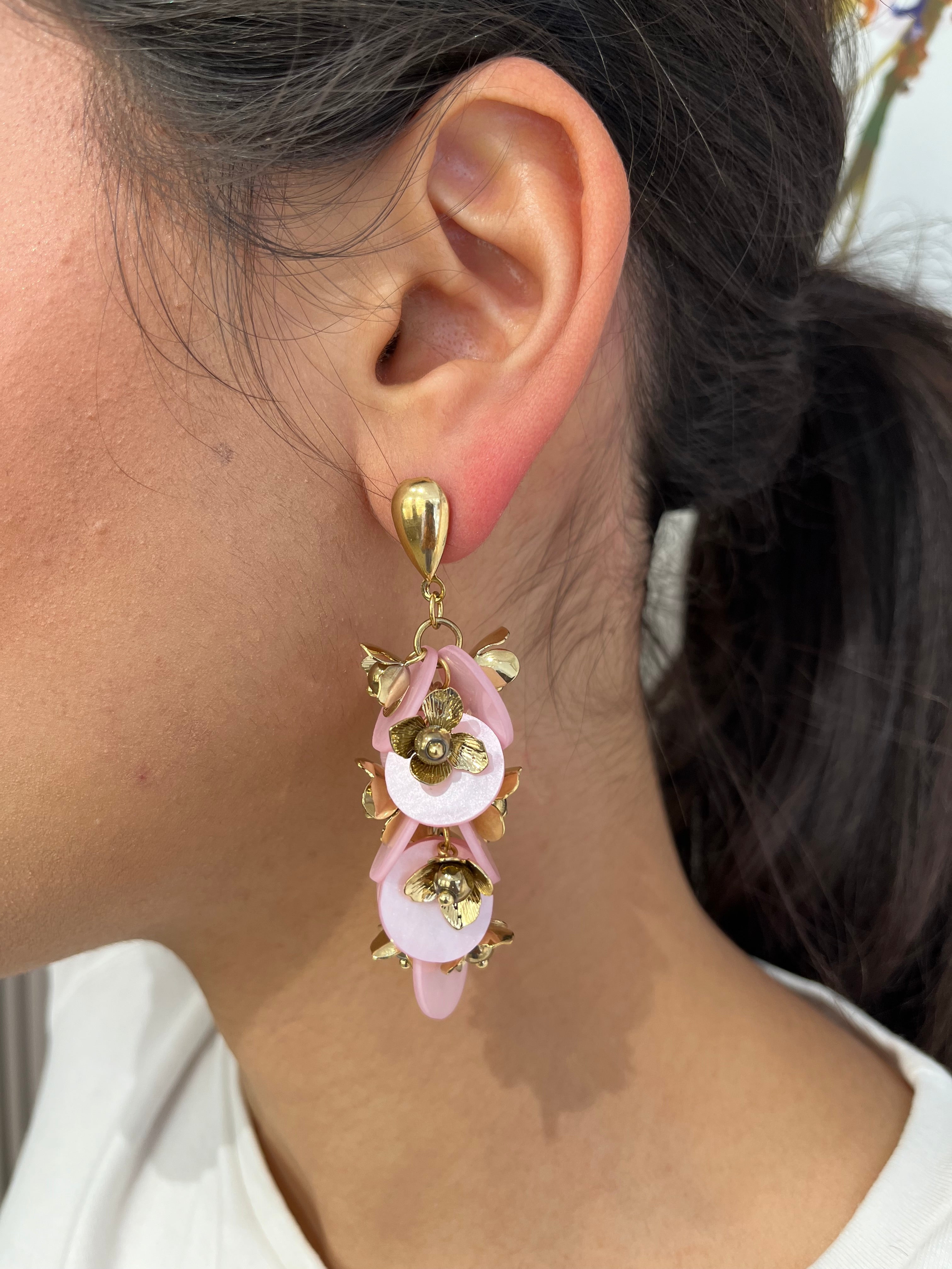 Grandes boucles d'oreilles Rich dorées avec motifs fleurs rose et dorées portées de profil.