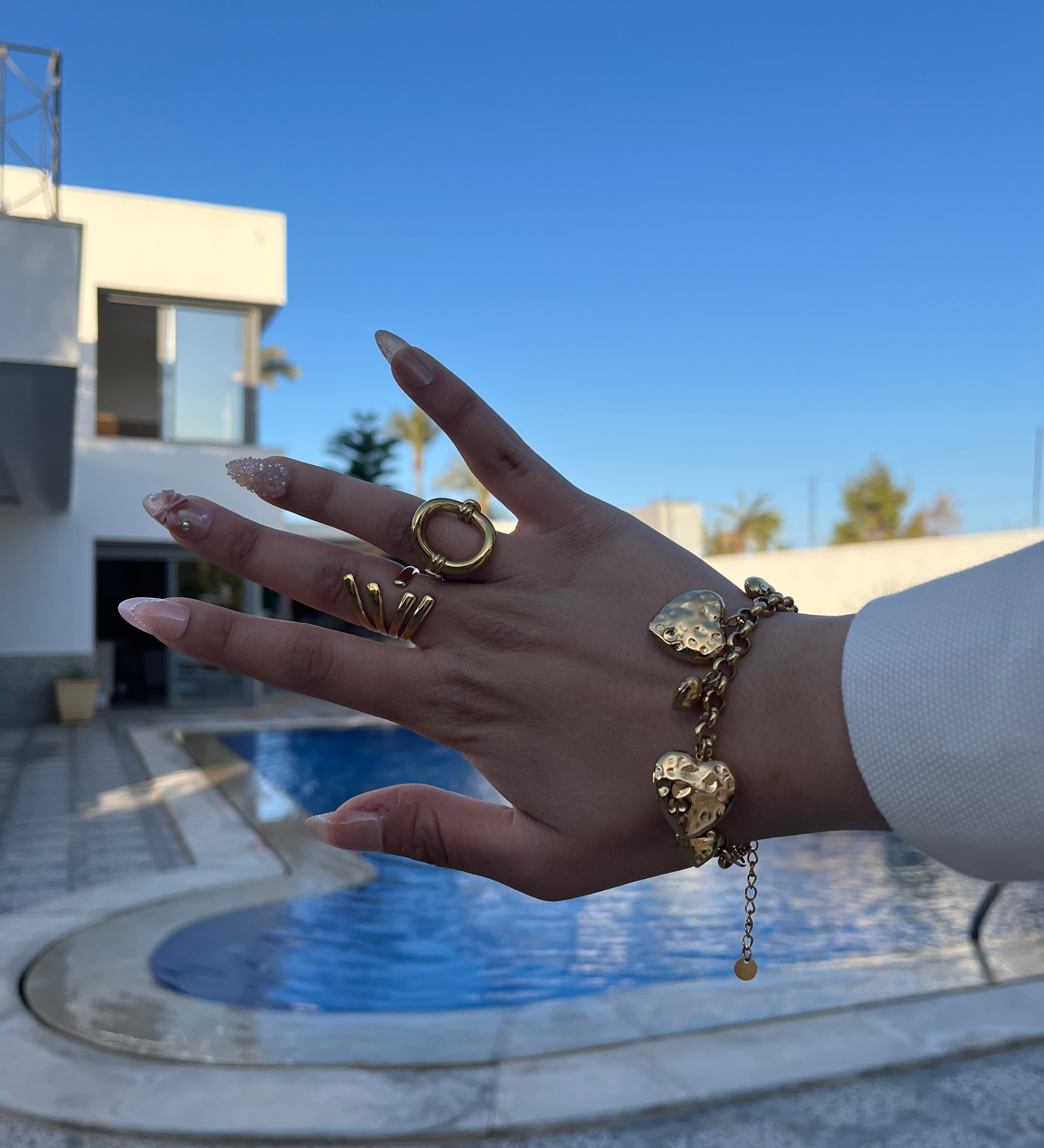 Femme portant le bracelet Ajim doré au bord d'une piscine, bijou Ordiajade en acier inoxydable