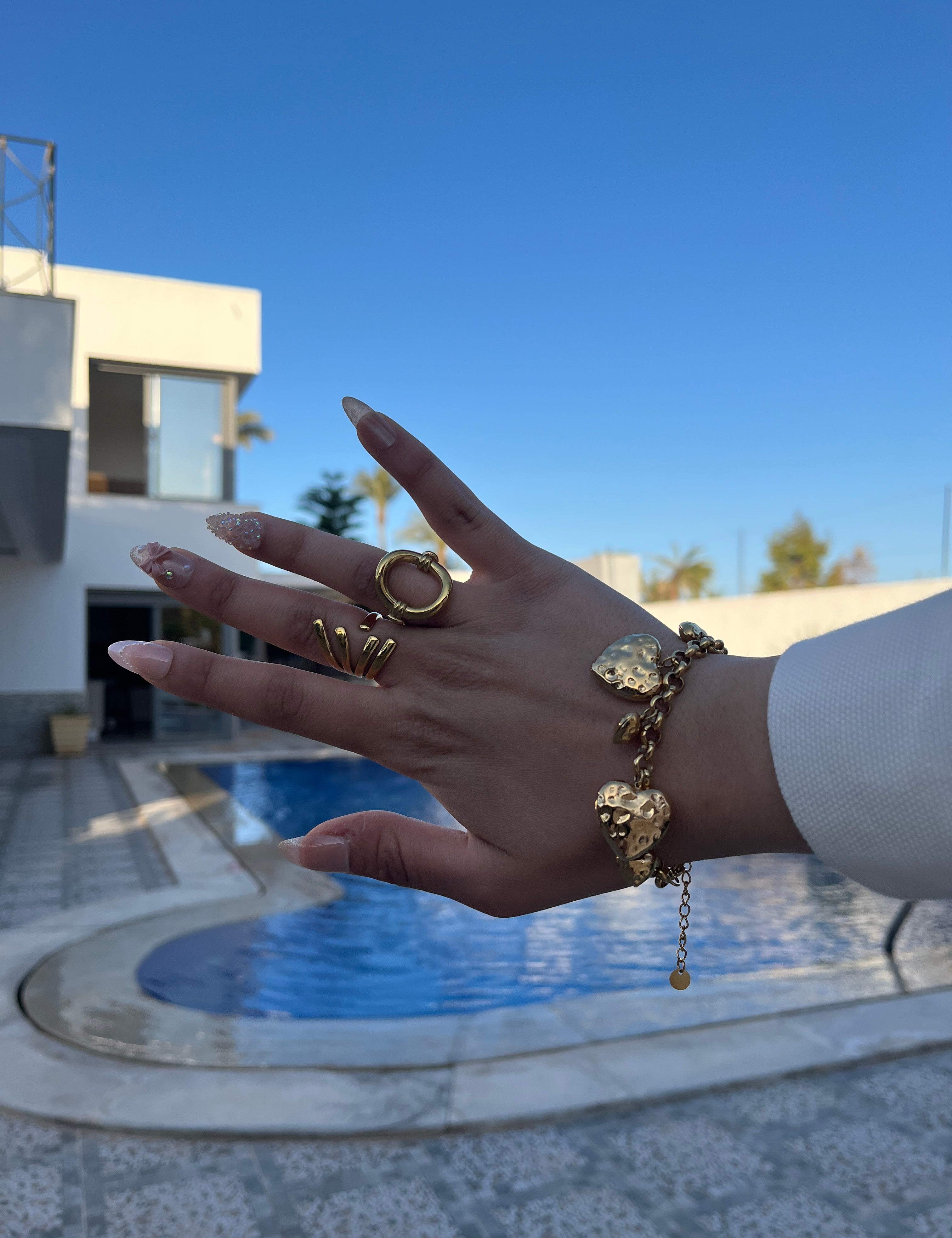 Femme portant le bracelet Ajim doré au bord d'une piscine, bijou Ordiajade en acier inoxydable