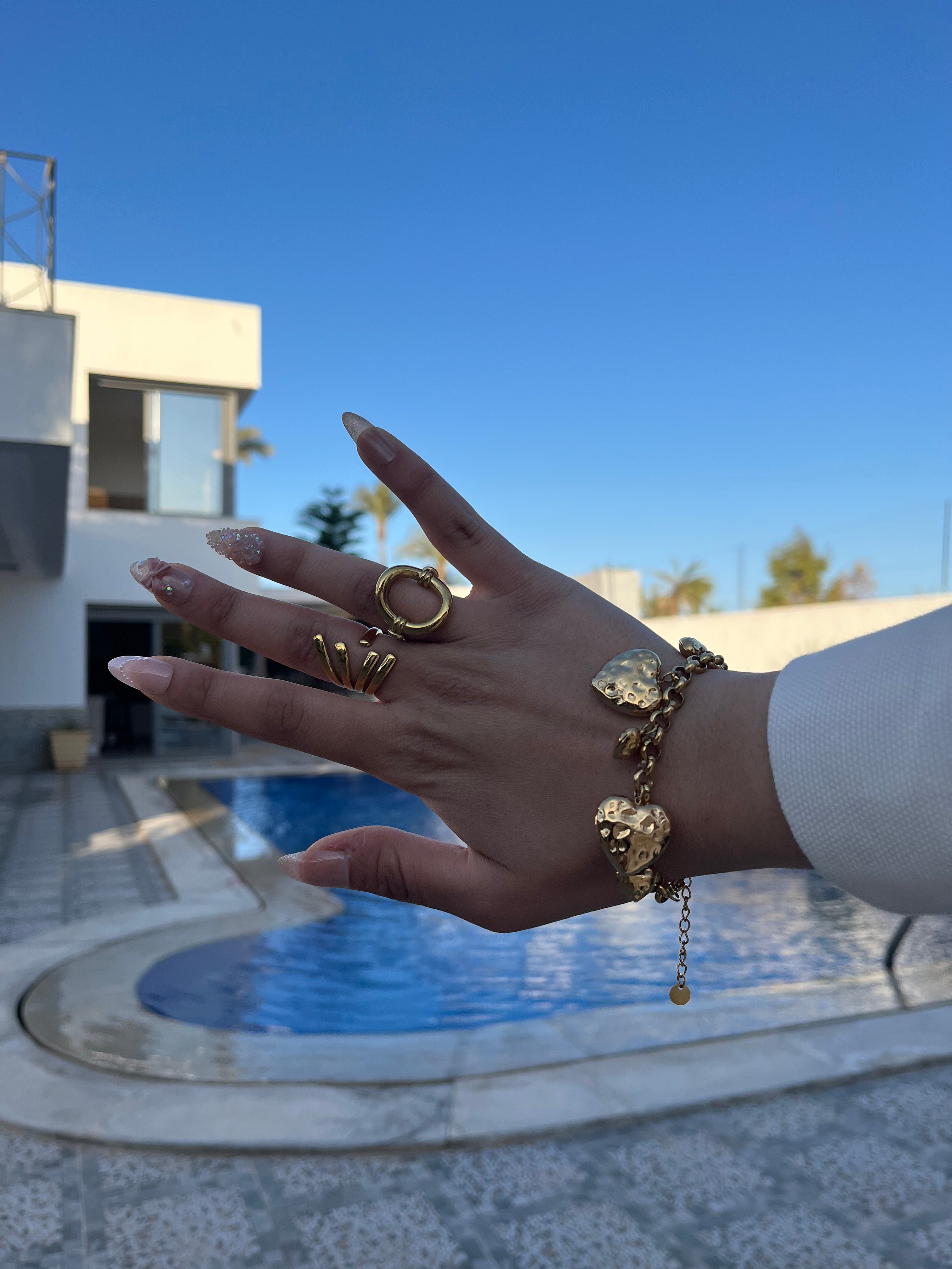 Femme portant le bracelet Ajim doré au bord d'une piscine, bijou Ordiajade en acier inoxydable