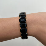 Découvre le bracelet élastique Black Swan en acier inoxydable doré et pierres noires. Un bijou extensible chic, confortable, résistant à l'eau et hypoallergénique.
