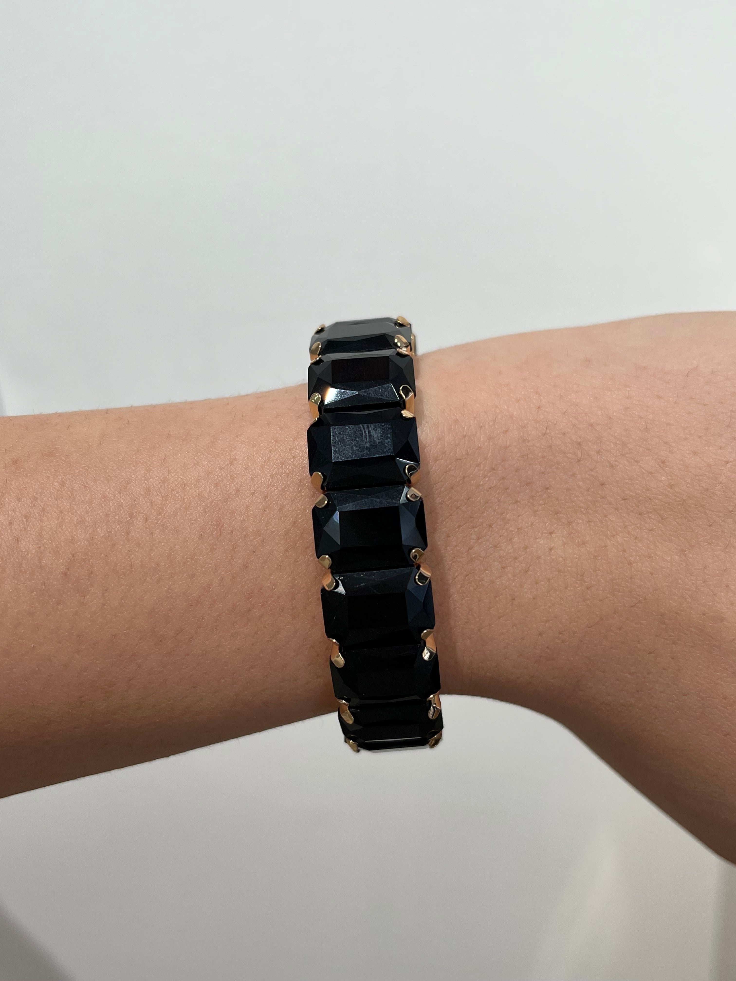 Découvre le bracelet élastique Black Swan en acier inoxydable doré et pierres noires. Un bijou extensible chic, confortable, résistant à l'eau et hypoallergénique.