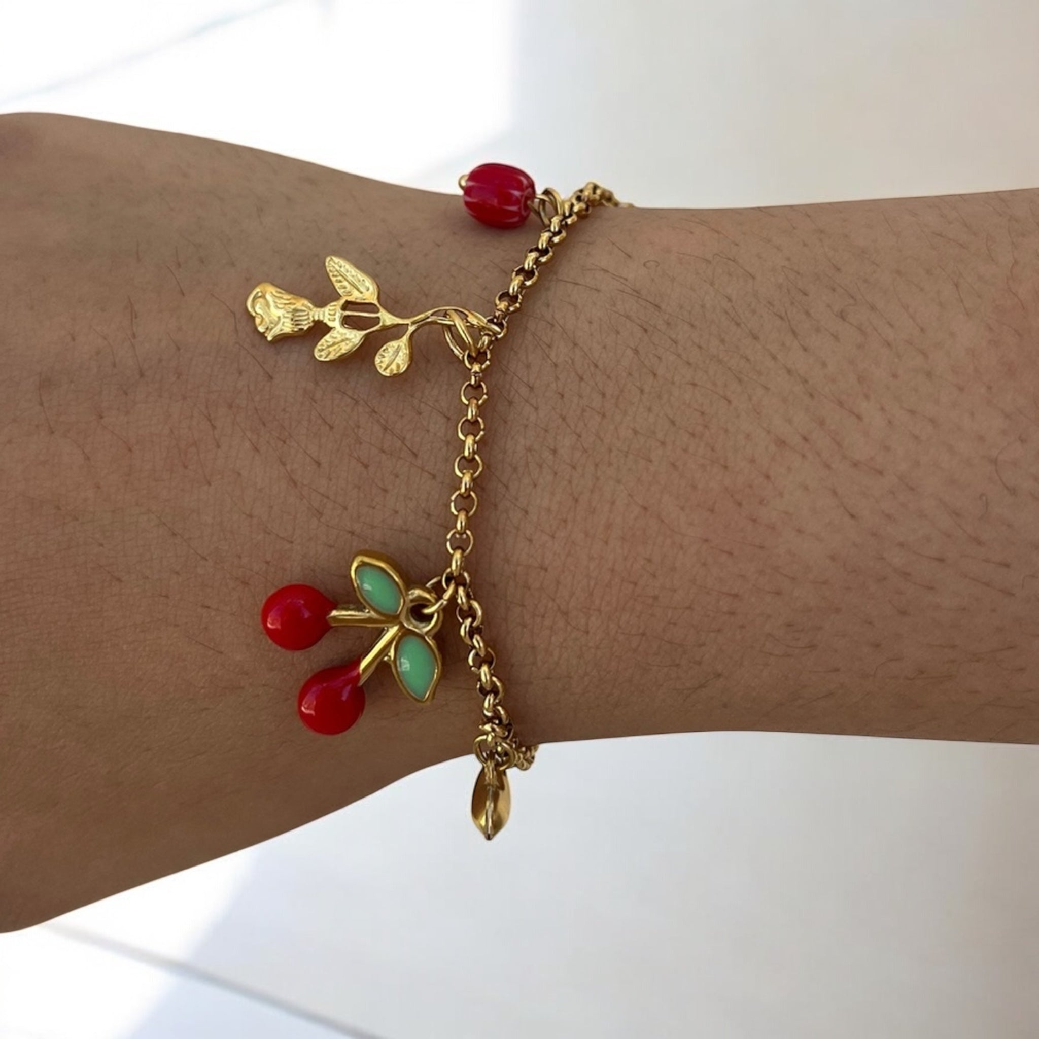 Bracelet Cerise à breloques cerises et feuilles dorées porté au poignet - Ordiajade
