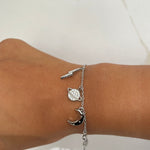 Bracelet argent à maillons fins avec breloques en forme d'éclair, de lune et de planète.