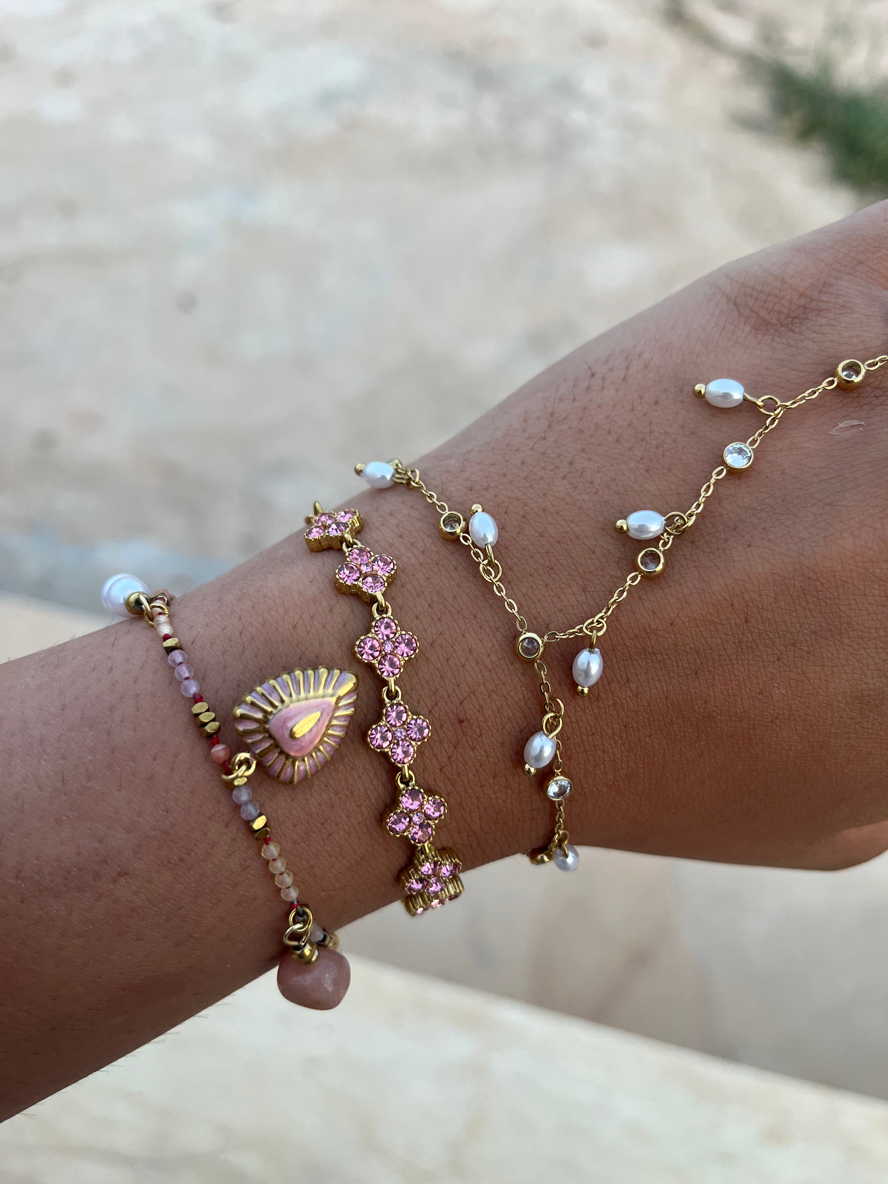 Accumulation de bracelets fins dorés au poignet mettant en valeur le bracelet Coraline en acier inoxydable aux pierres facettées roses - Ordiajade