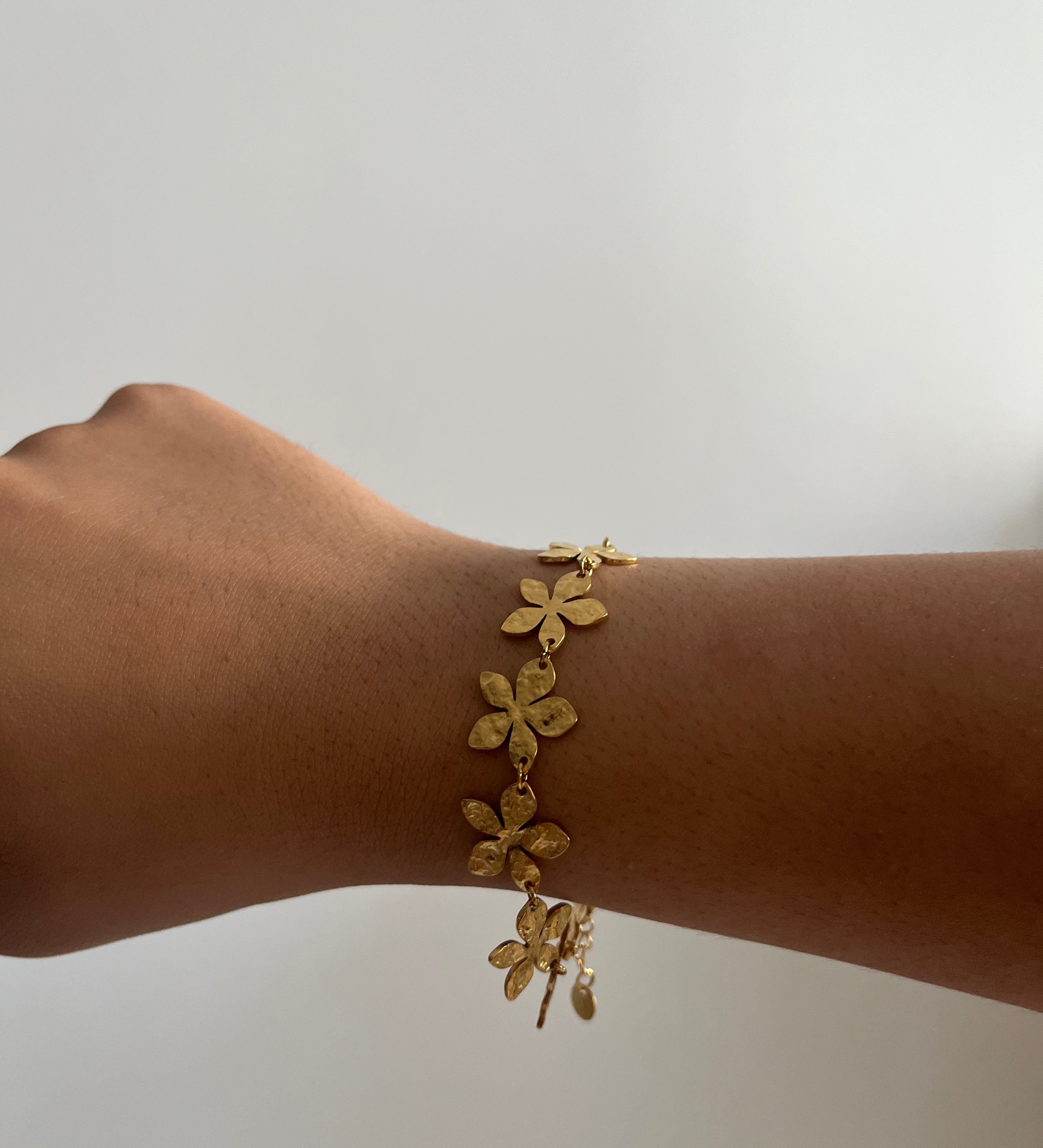 Bracelet Eden doré en acier inoxydable avec des motifs floraux délicats porté au poignet Ordiajade