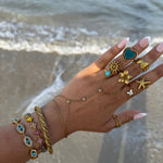 Gros plan du bracelet doré EYE porté au poignet en accumulation avec d'autres bijoux - Ordiajade