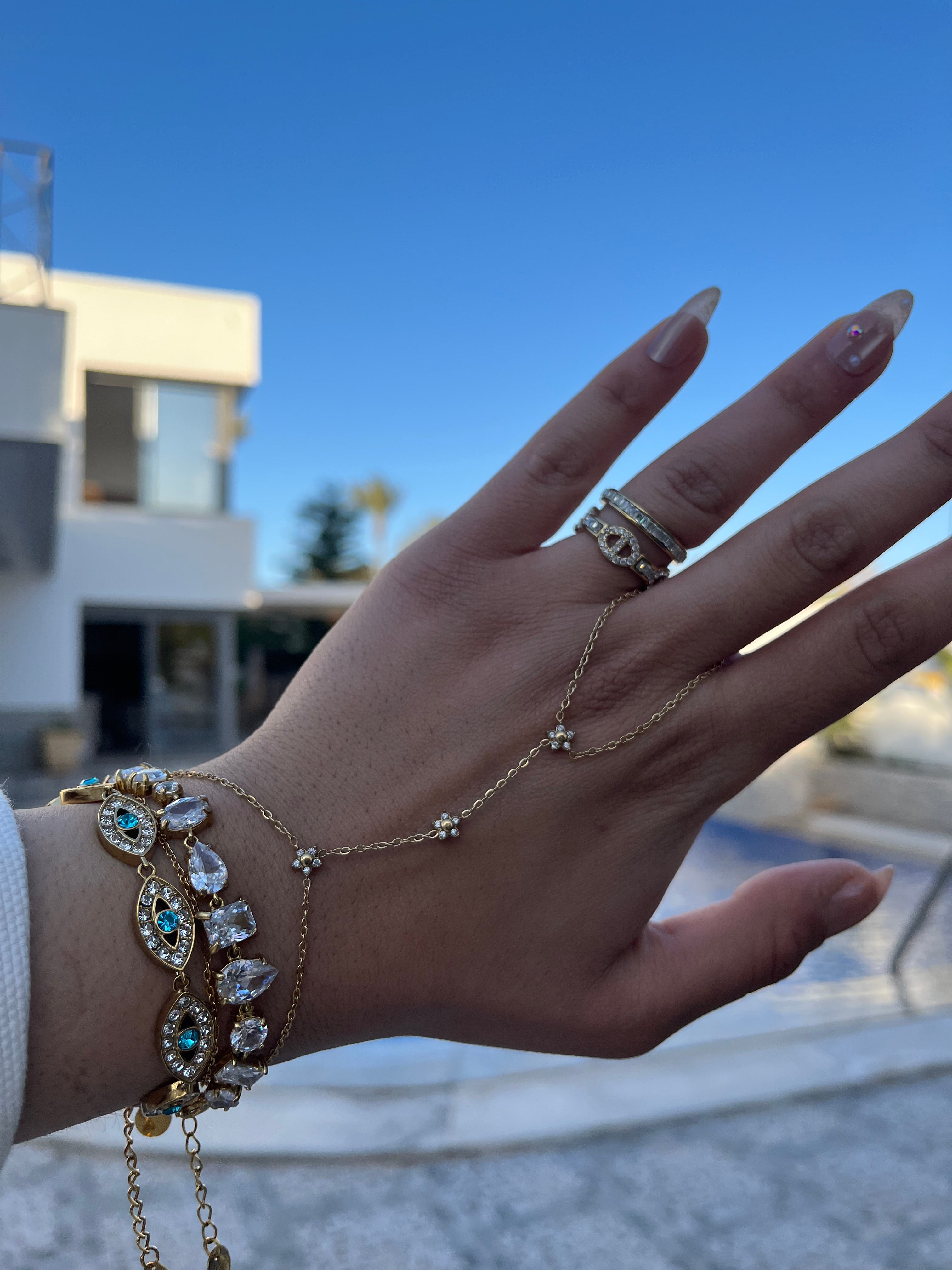 Gros plan du bracelet doré EYE porté au poignet en accumulation avec d'autres bijoux - Ordiajade