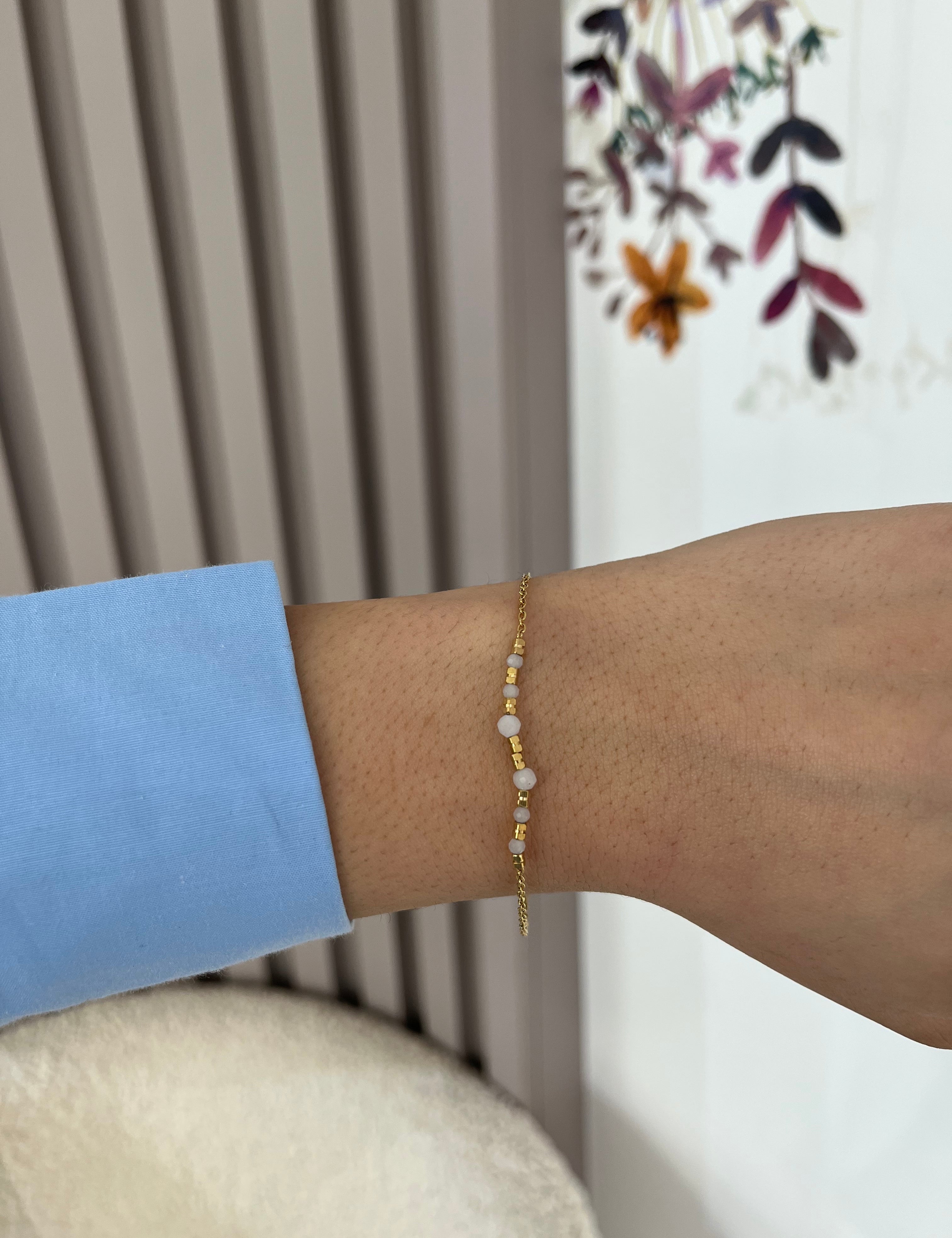 Bracelet Lauria fin en acier inoxydable doré à perles blanches porté au poignet - Ordiajade