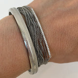 Gros plan sur les fines chaînes argentées du bracelet multirangs Lyv.