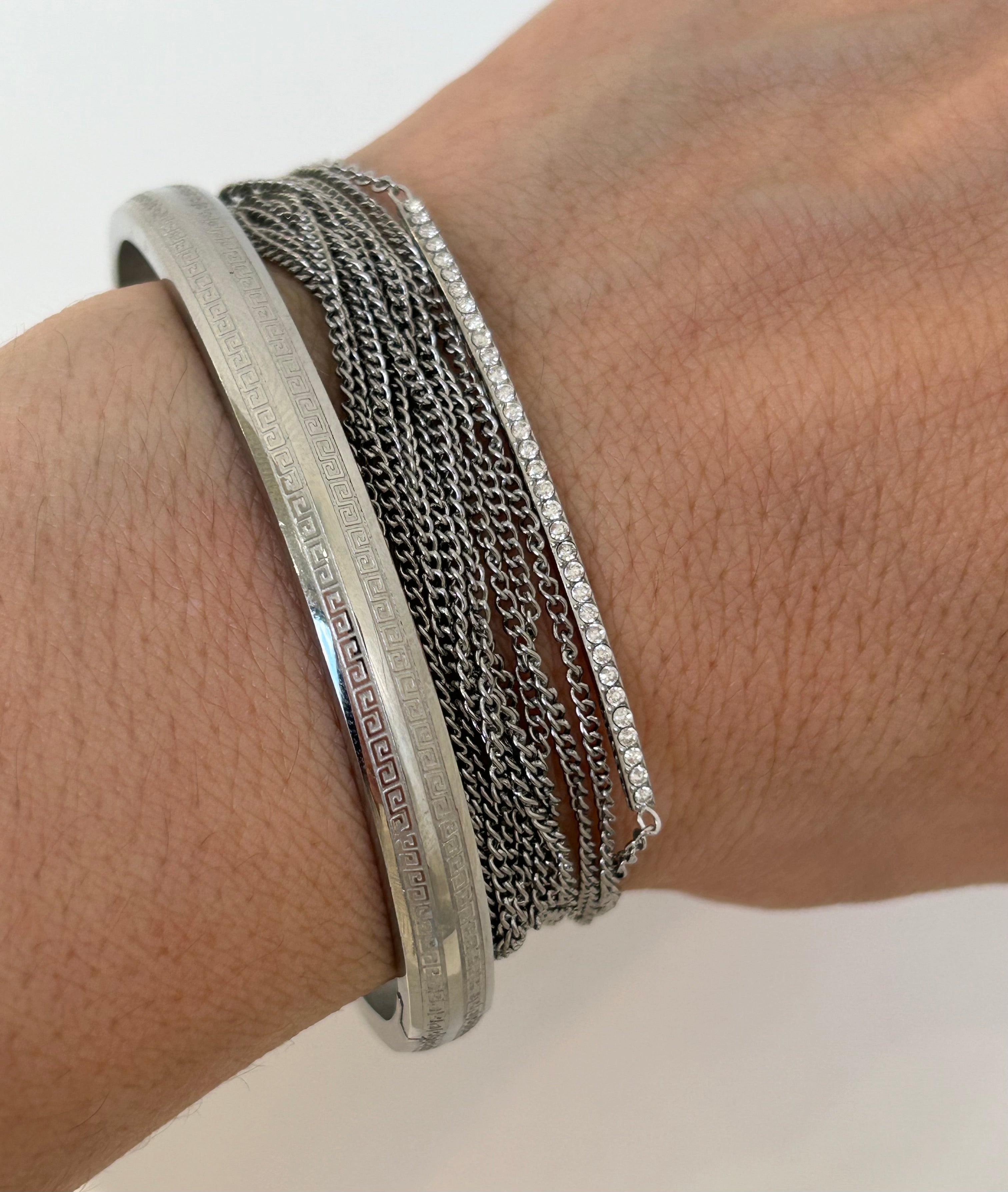 Gros plan sur les fines chaînes argentées du bracelet multirangs Lyv.