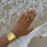 Manchette Sultana dorée portée au poignet d'une femme à la plage.